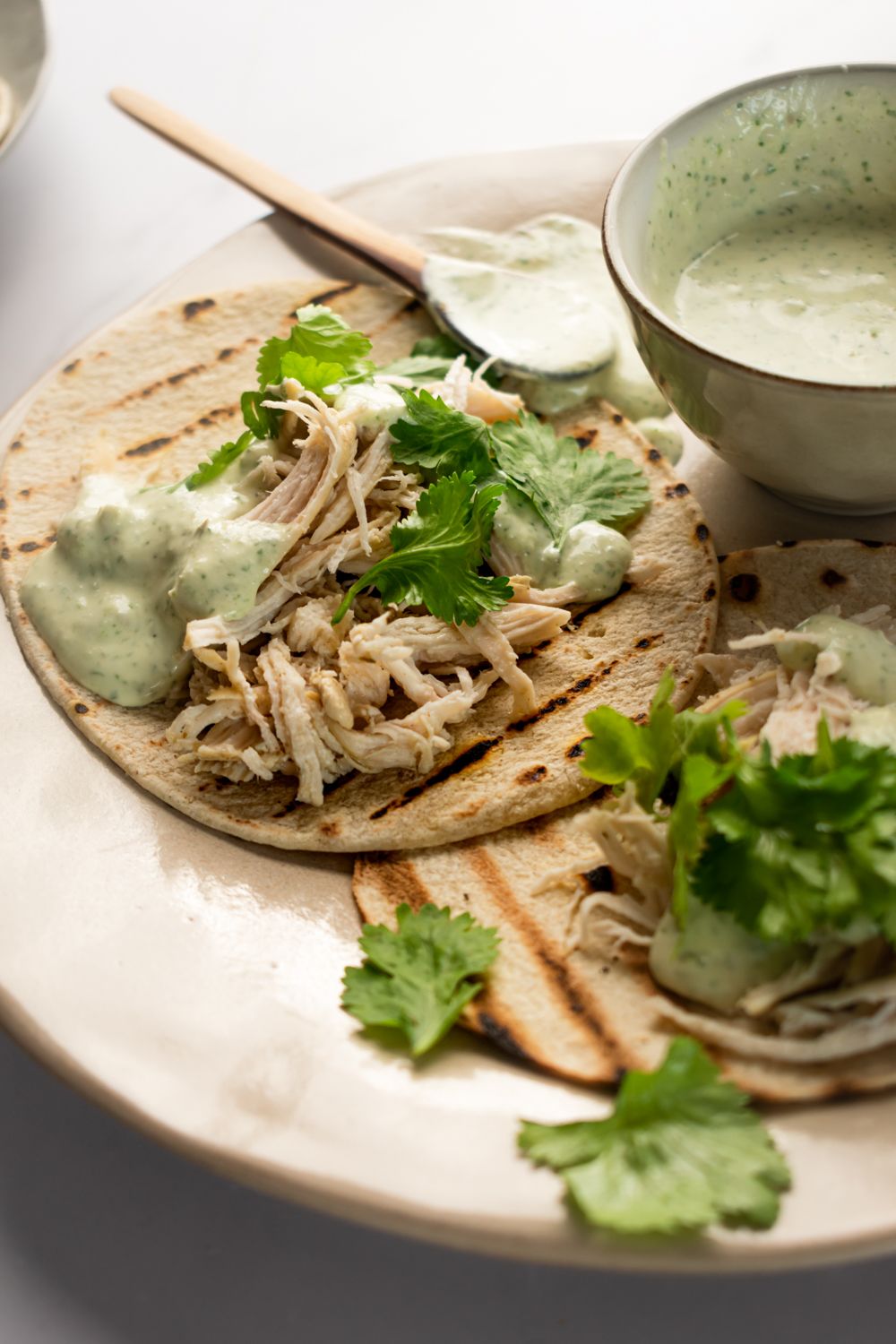 Jalapeno chicken tacos on corn tortillas with a creamy yogurt cilantro sauce drizzled on top.