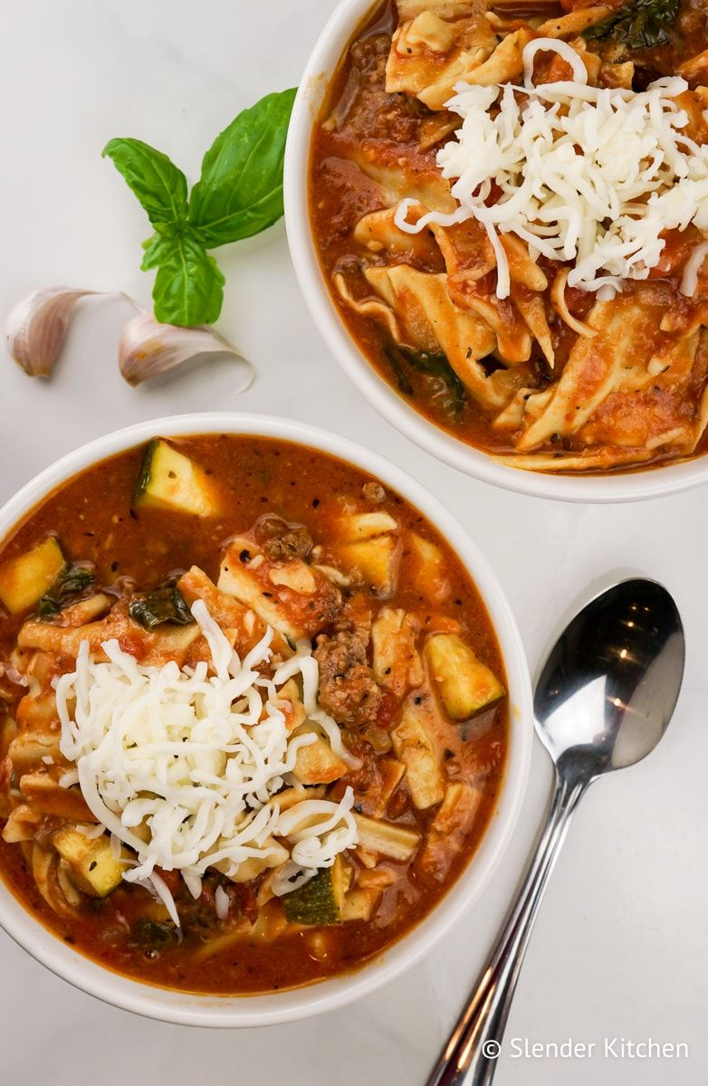 Healthy Slow Cooker Lasagna Soup in a bowl with fresh basil and mozzarella cheese.