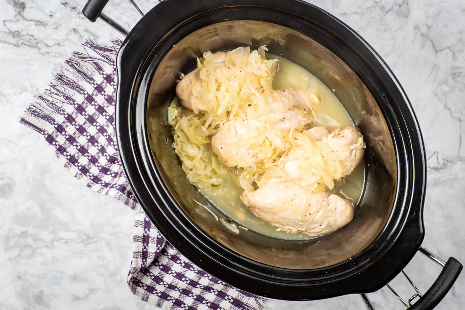 Slow cooker garlic lemon chicken in a crockpot after being cooked with onions.