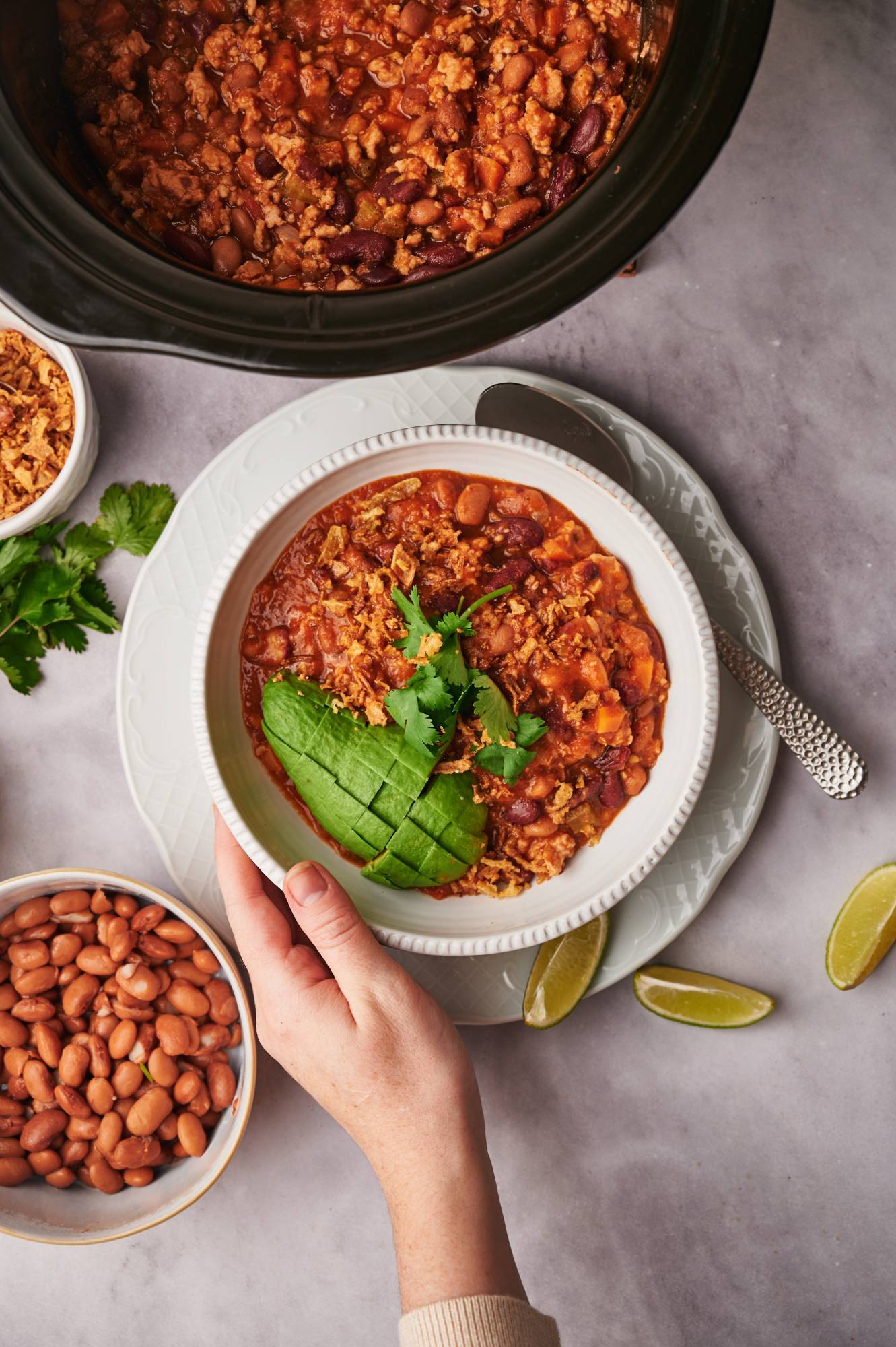 Crockpot turkey chili with beans, ground turkey, and tomatoes in a bowl with cilantro and avocado.