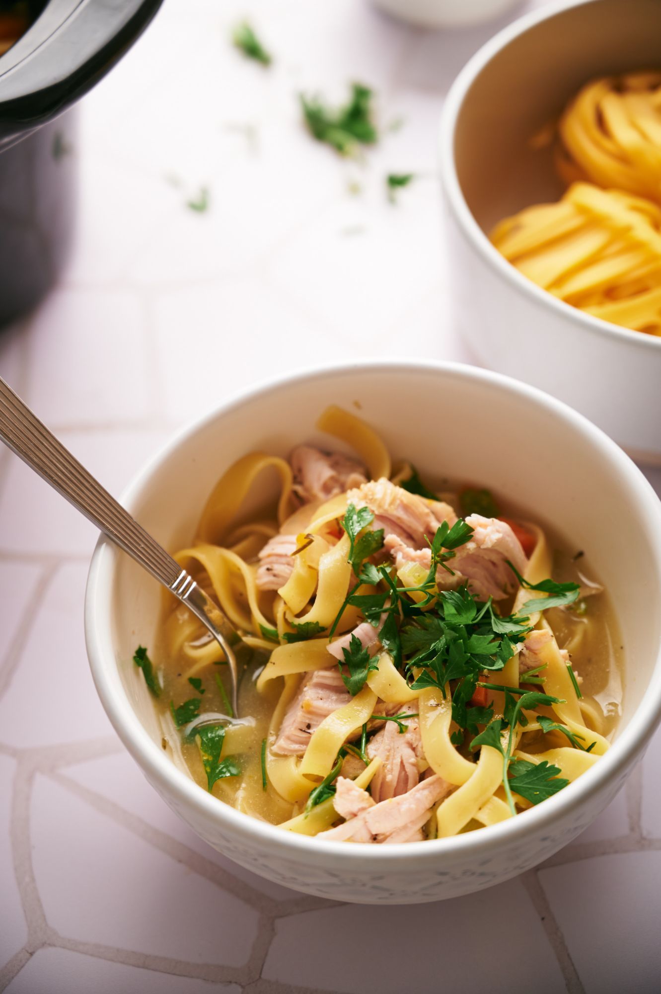 Crockpot turkey soup in a bowl with egg noodles, shredded turkey, carrots, and fresh parsley