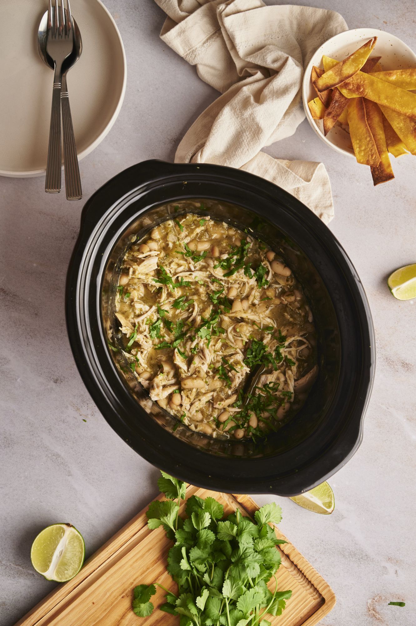 Crockpot white chicken chili with white beans, shredded chicken, and cilantro in a black slow cooker.