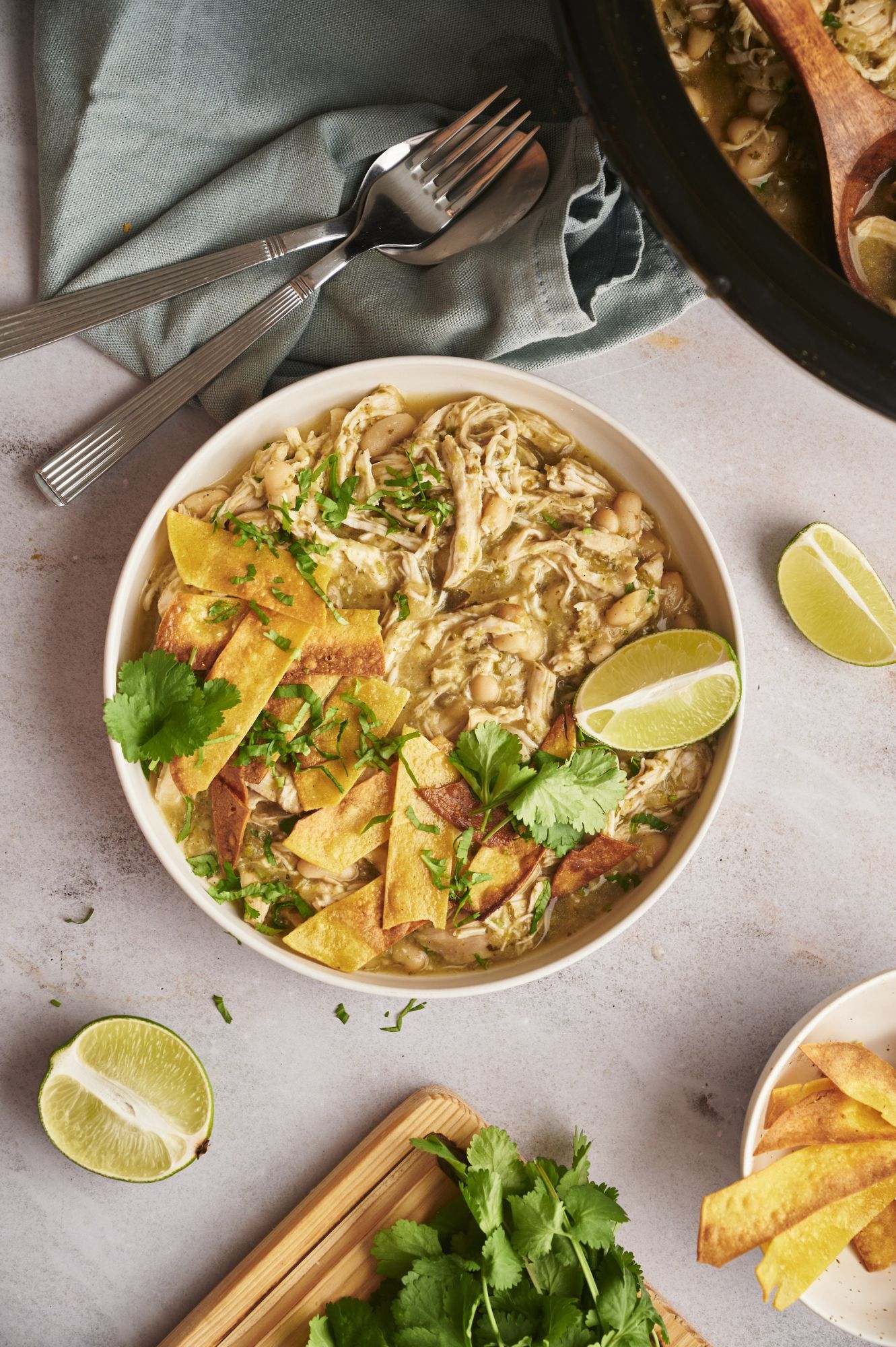 White chicken chili served in a bowl with tortilla chips, lime, and cilantro.