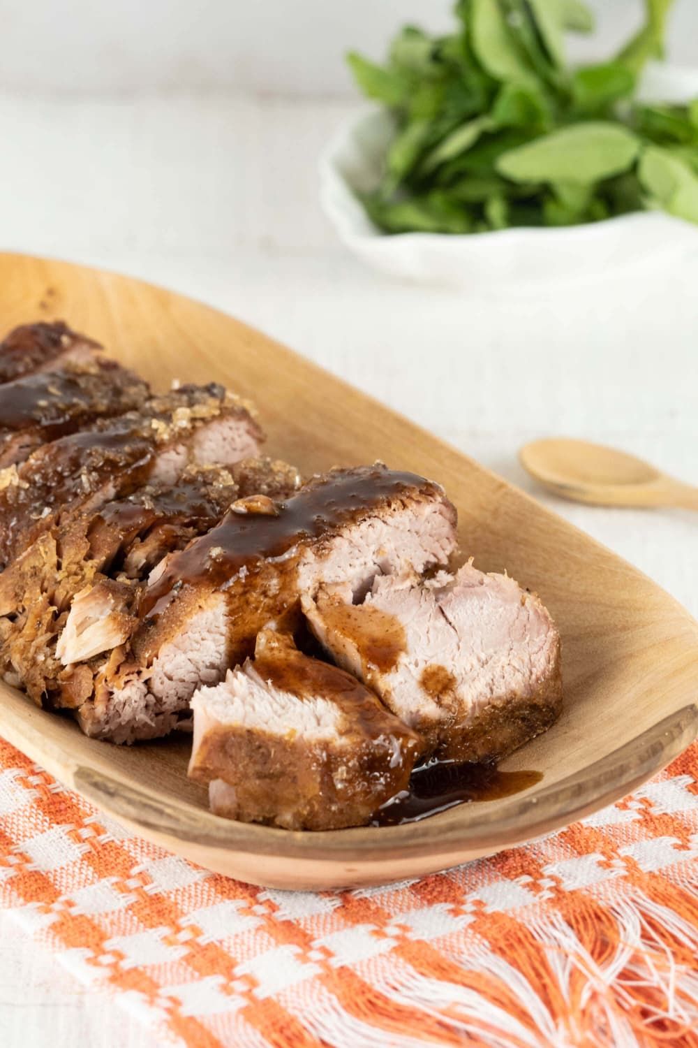 Crockpot Balsamic Pork Tenderloin cut into slices on a wooden plate.