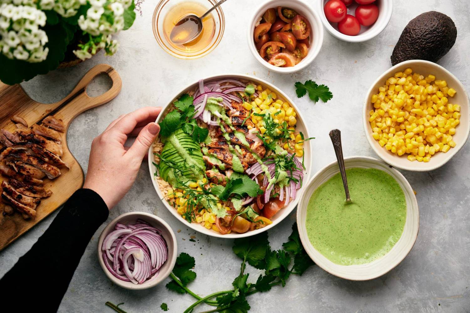 Grilled Southwestern chicken rice bowls with cilantro lime sauce, corn, avocado, and vegetables served with cilantro.