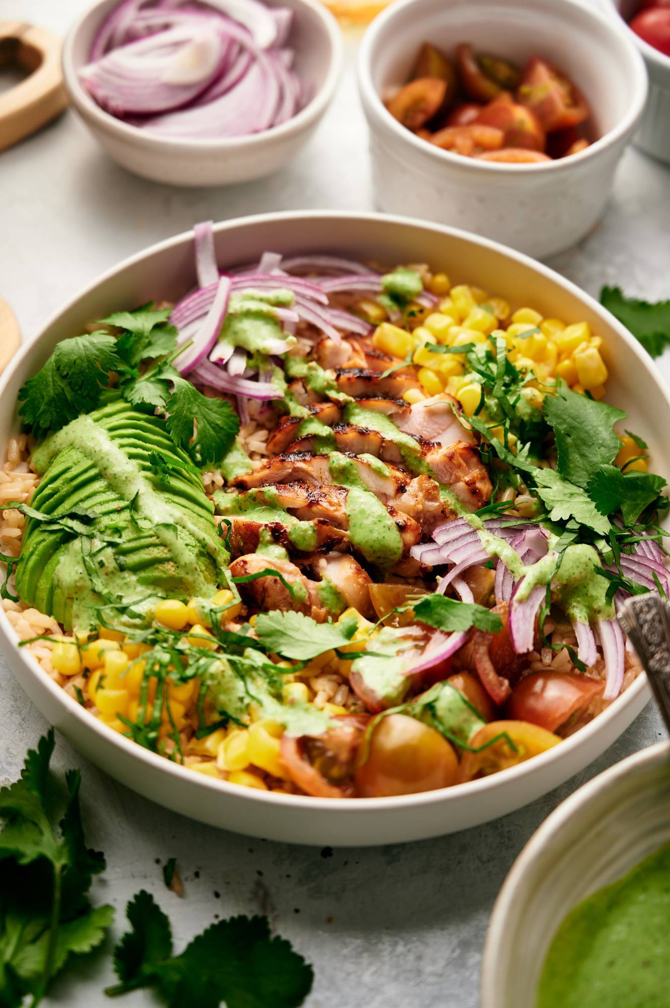 Chicken rice bowls with Southwestern flavors including brown rice, grilled chicken, corn, onion, tomatoes, and cilantro lime sauce.