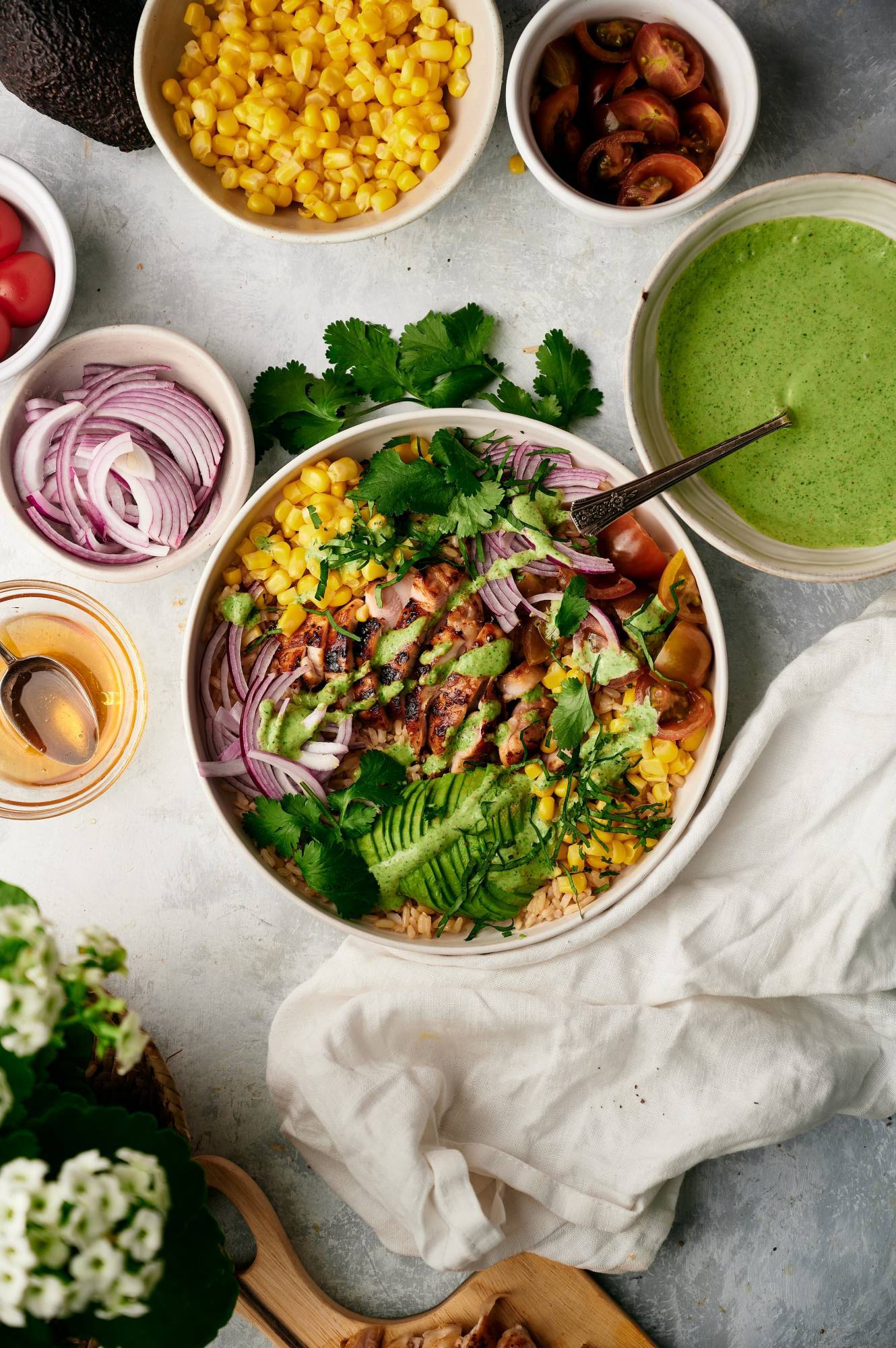 Southwest rice and chicken bowl with corn, avocado, red onion, cherry tomatoes, and cilantro sauce in a bowl.