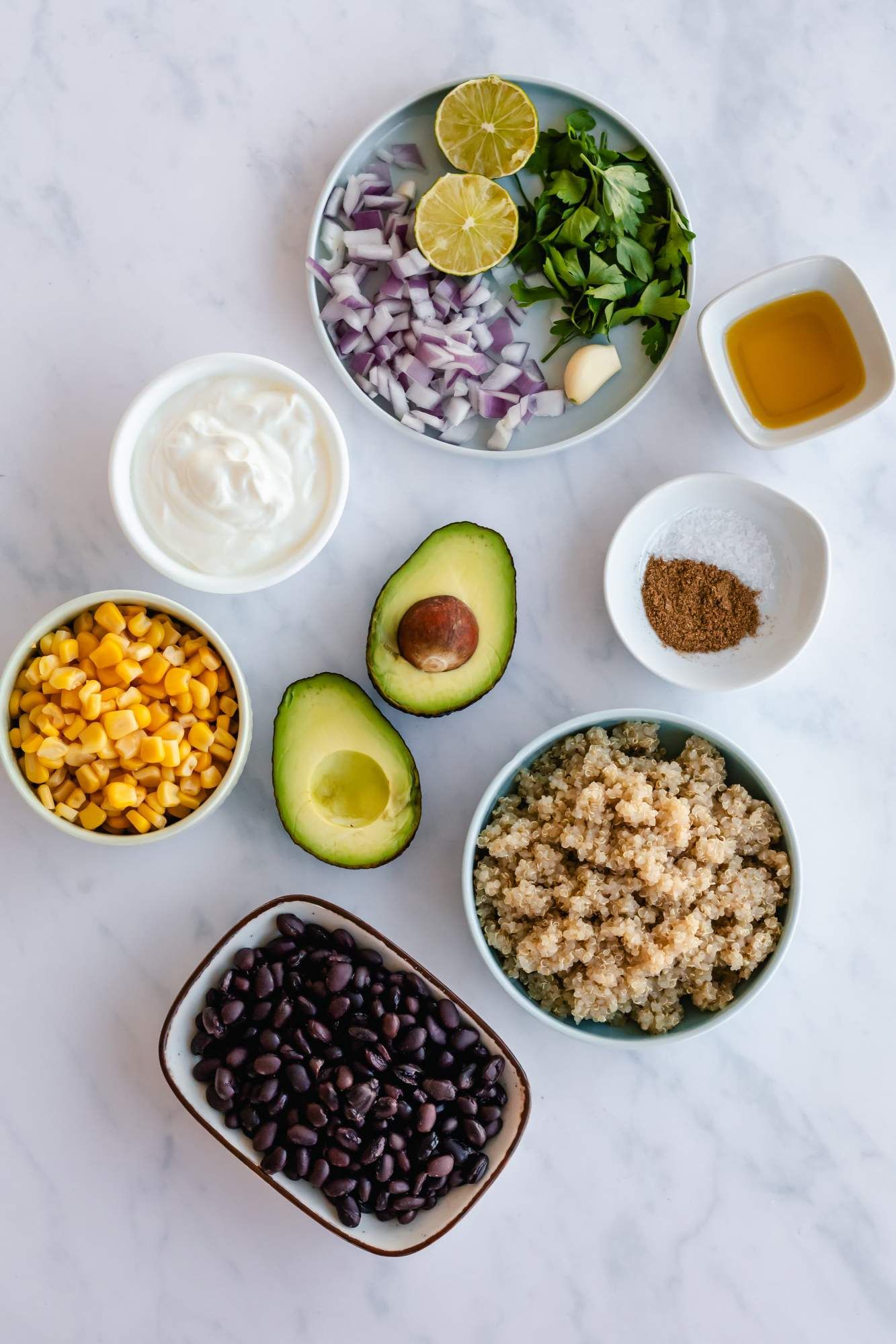 Ingredients for Southwest Quinoa salad including black beans, cooked quinoa, avocado, corn, red onion, avocado, cilanto, and limes.