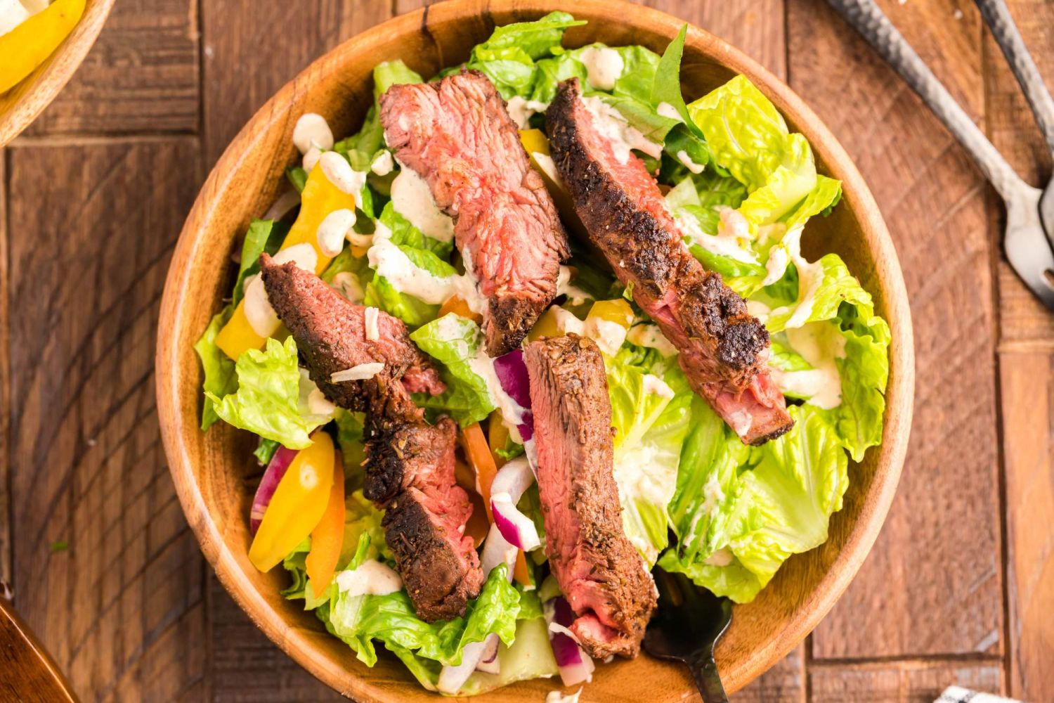 Steak salad with creamy southwest salad dressing, peppers, onions, steak, and Romaine lettuce.