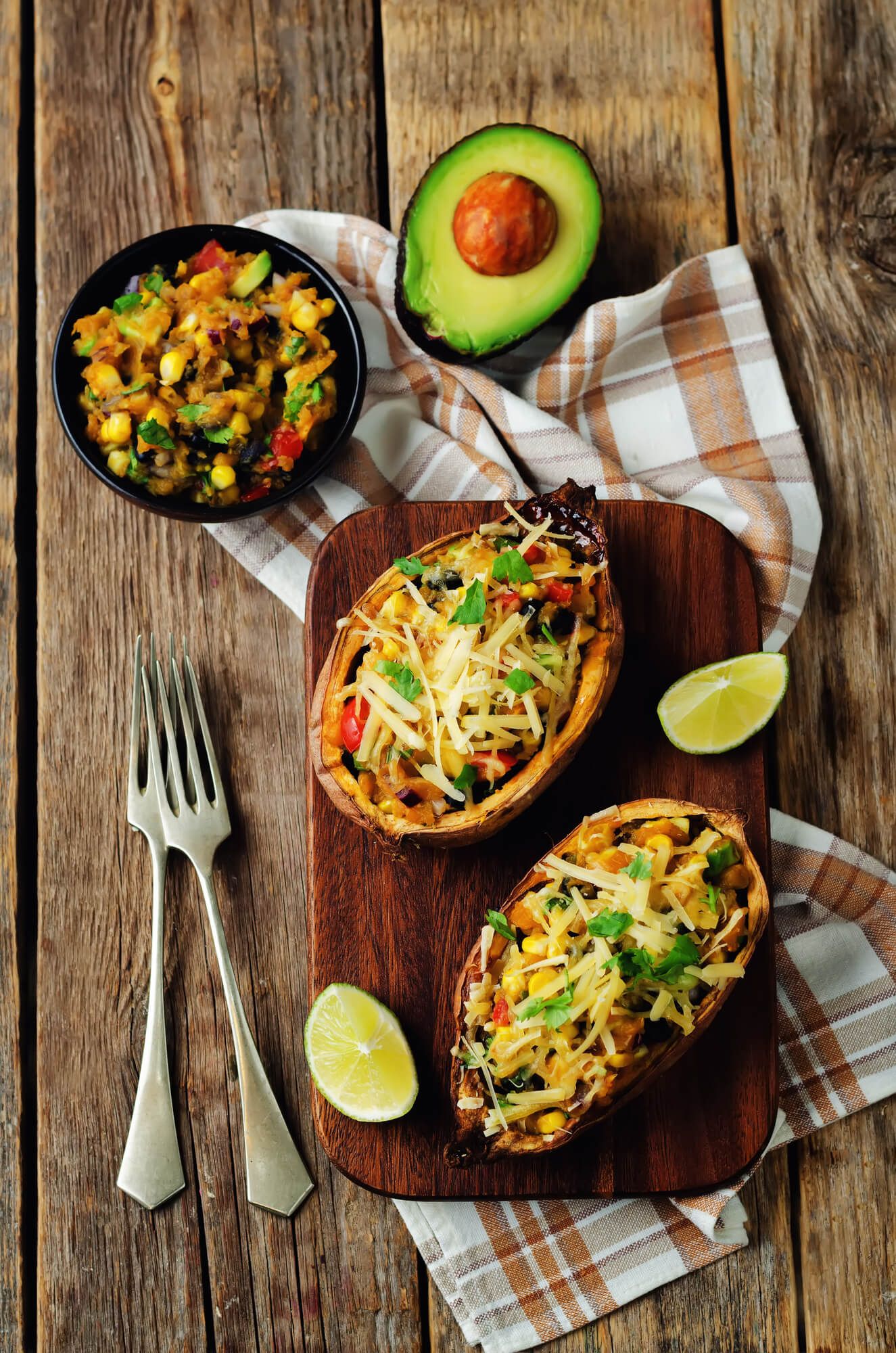 Southwest stuffed baked sweet potatoes with corn, black beans, green pepper, tomatoes, and shredded cheese.