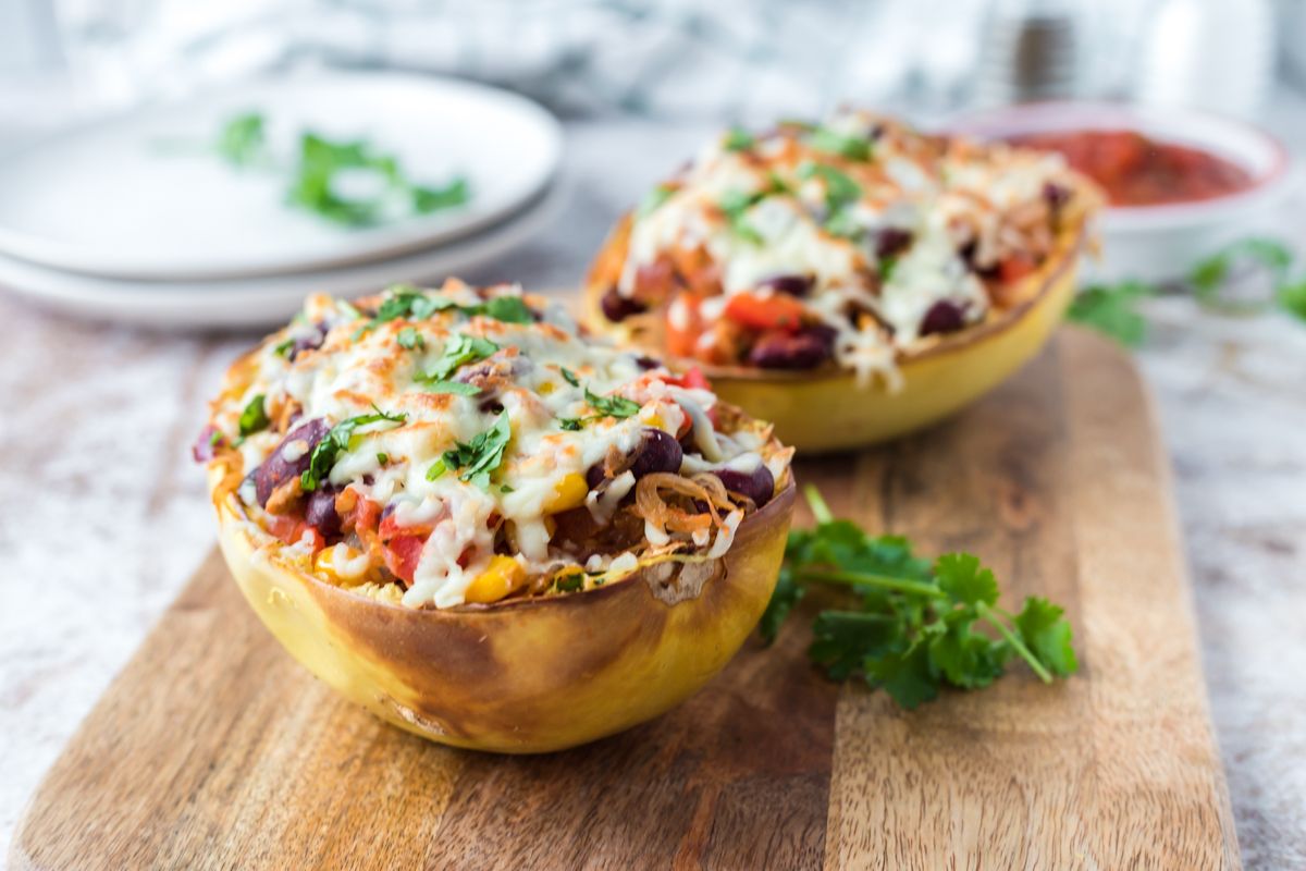 Spaghetti squash stuffed with burrito filling including beans, corn, tomatoes, salsa, and melted cheese.