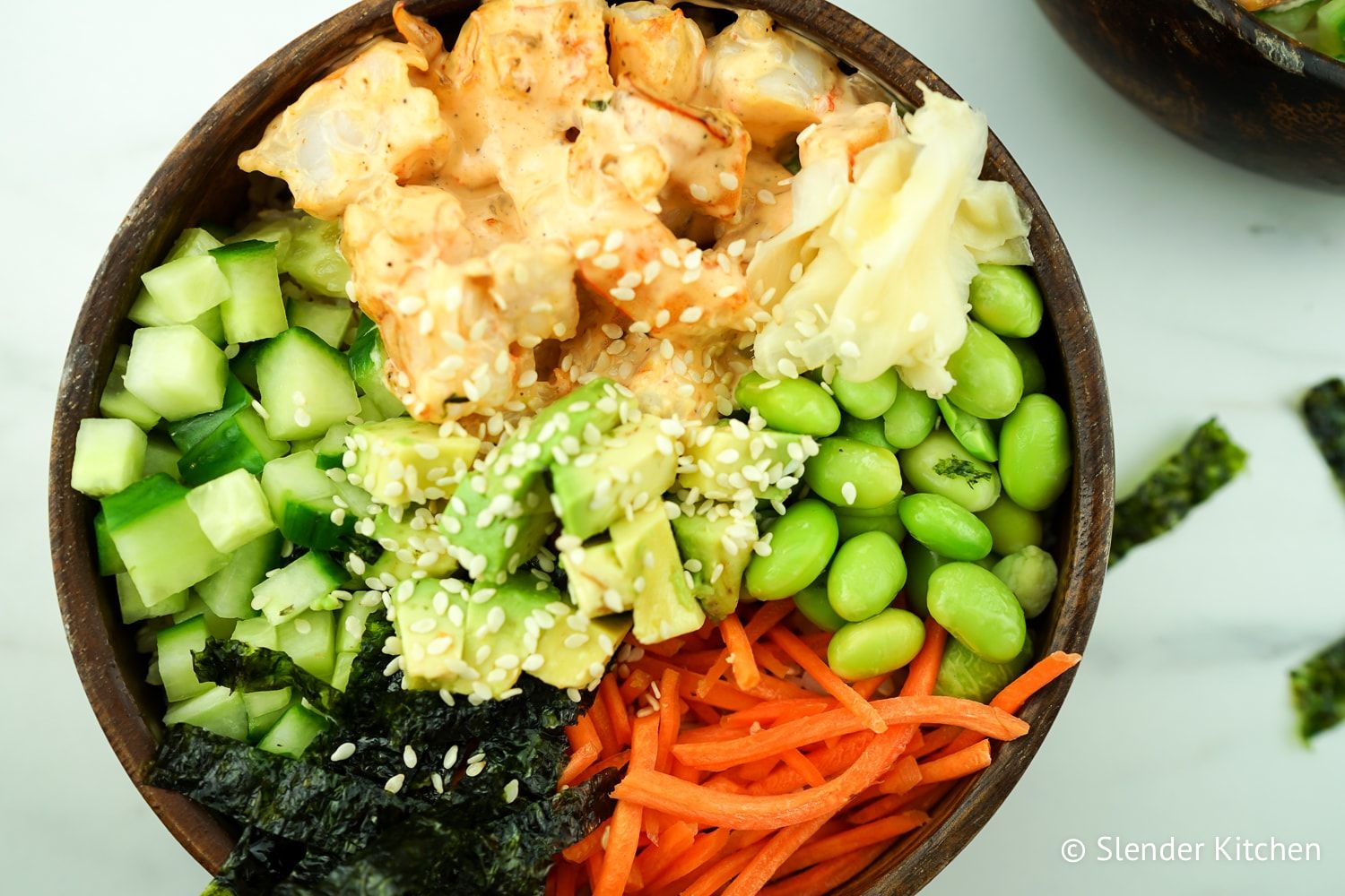 Healthy shrimp sushi bowls with avocado, edamame, carrots, and cucumbers in a wooden bowl.