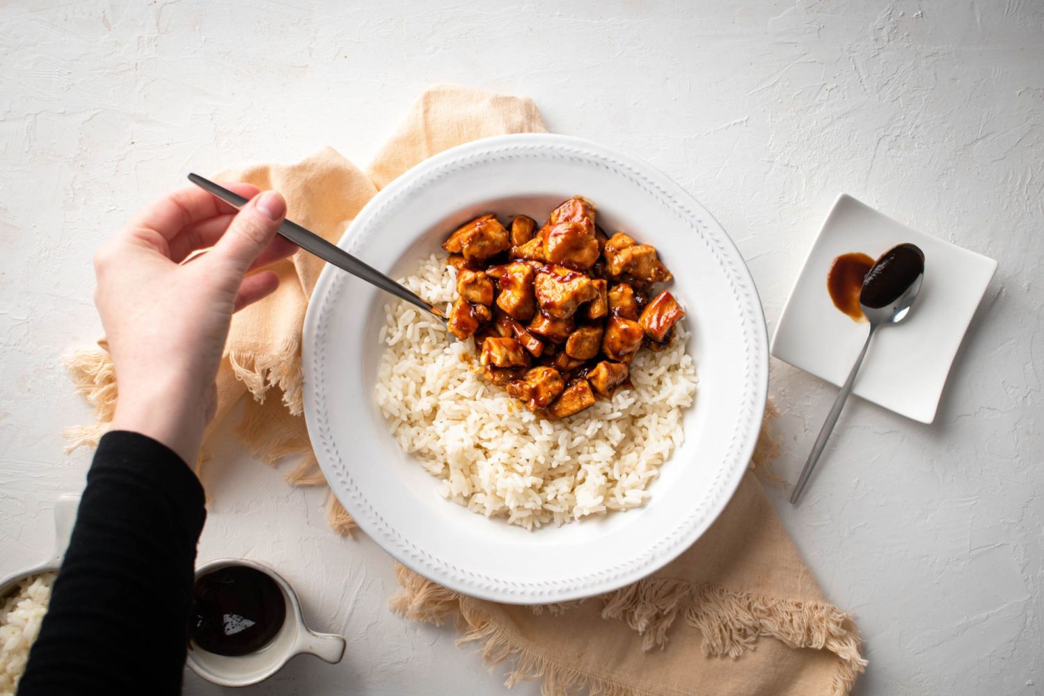 Chicken breast cooked in spicy hoisin sauce served in a bowl with steamed rice.