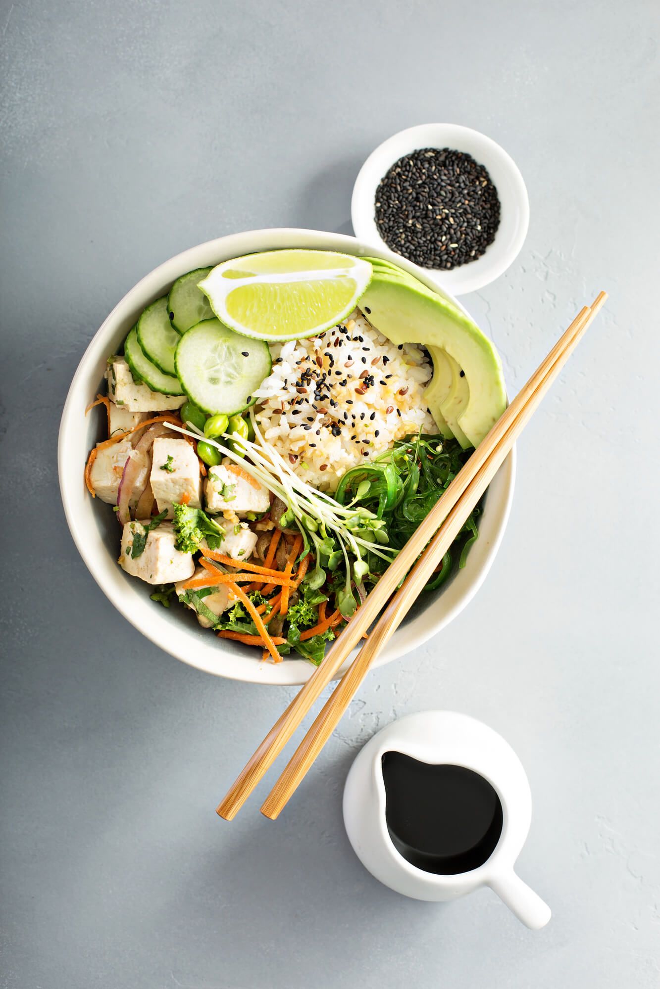 Vegetarian sushi bowl with edamame, pea shoots, avocado, tofu, and sesame seeds.