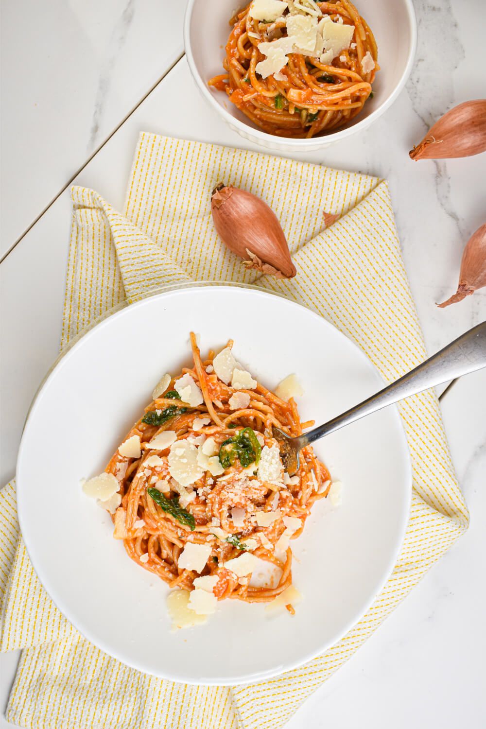 Tomato Spinach pasta in a bowl with wilted spinach, spaghetti, and parmesan cheese.