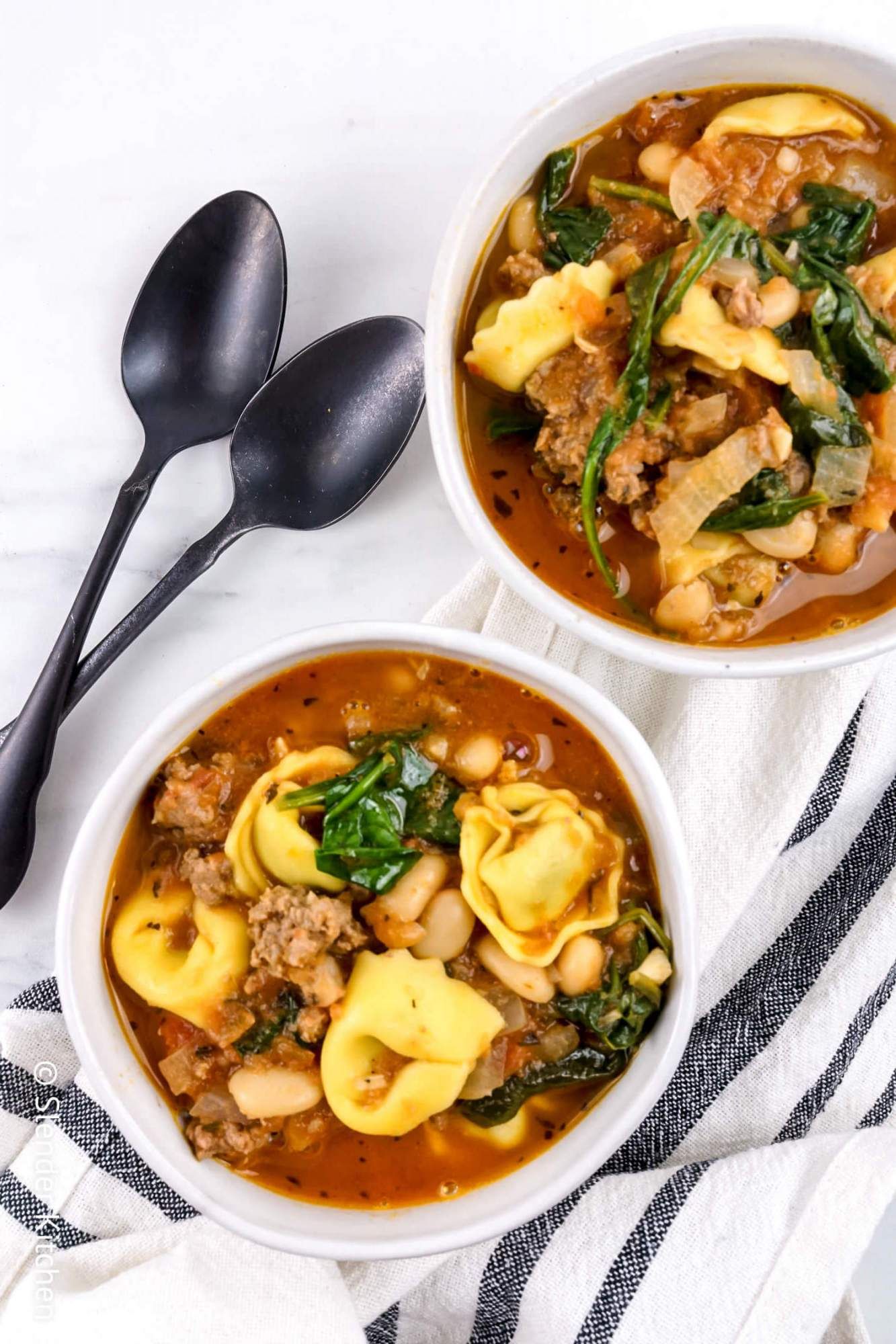 Easy tortellini soup in a bowl with white beans, turkey, spinach, and tomatoes.