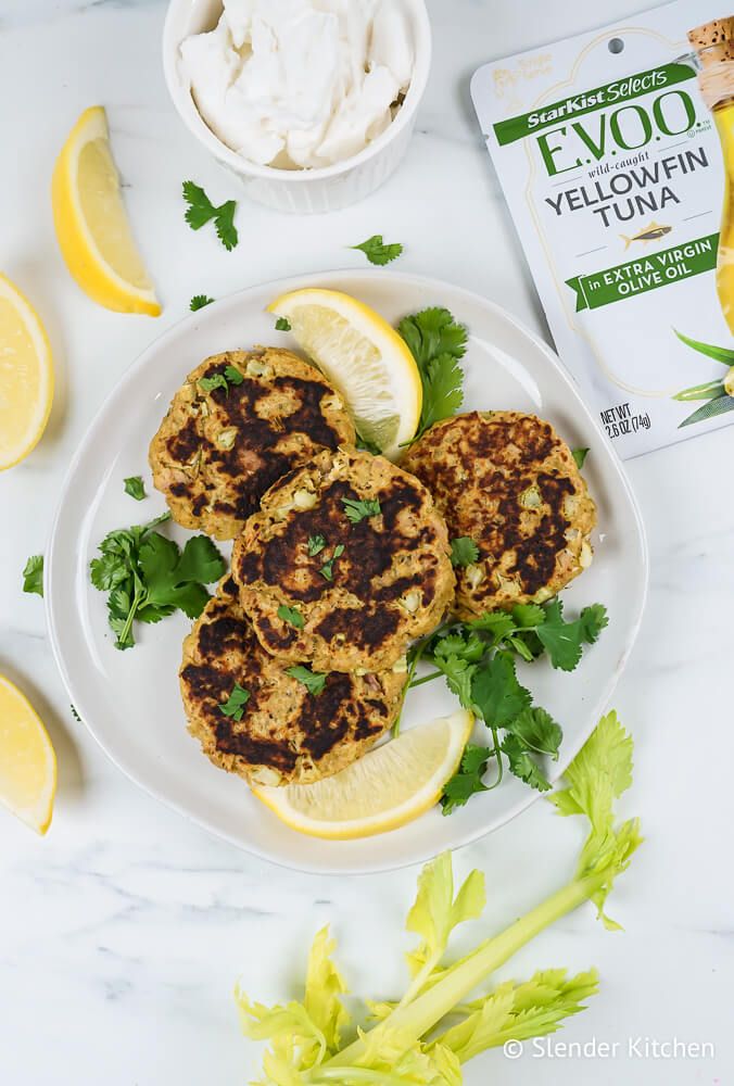 Tuna patties on a plate with celery, Greek yogurt, lemon, breadcrumbs, and tuna.