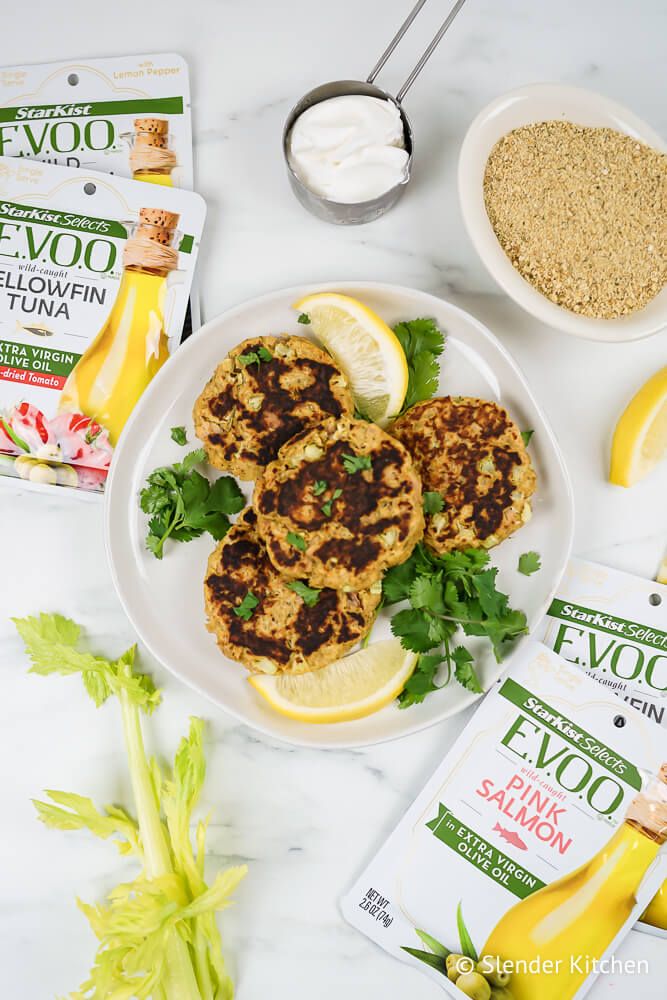 Patties made with tuna, breadcrumbs, celery, yogurt, and egg cooked and piled on a plate with fresh lemon.