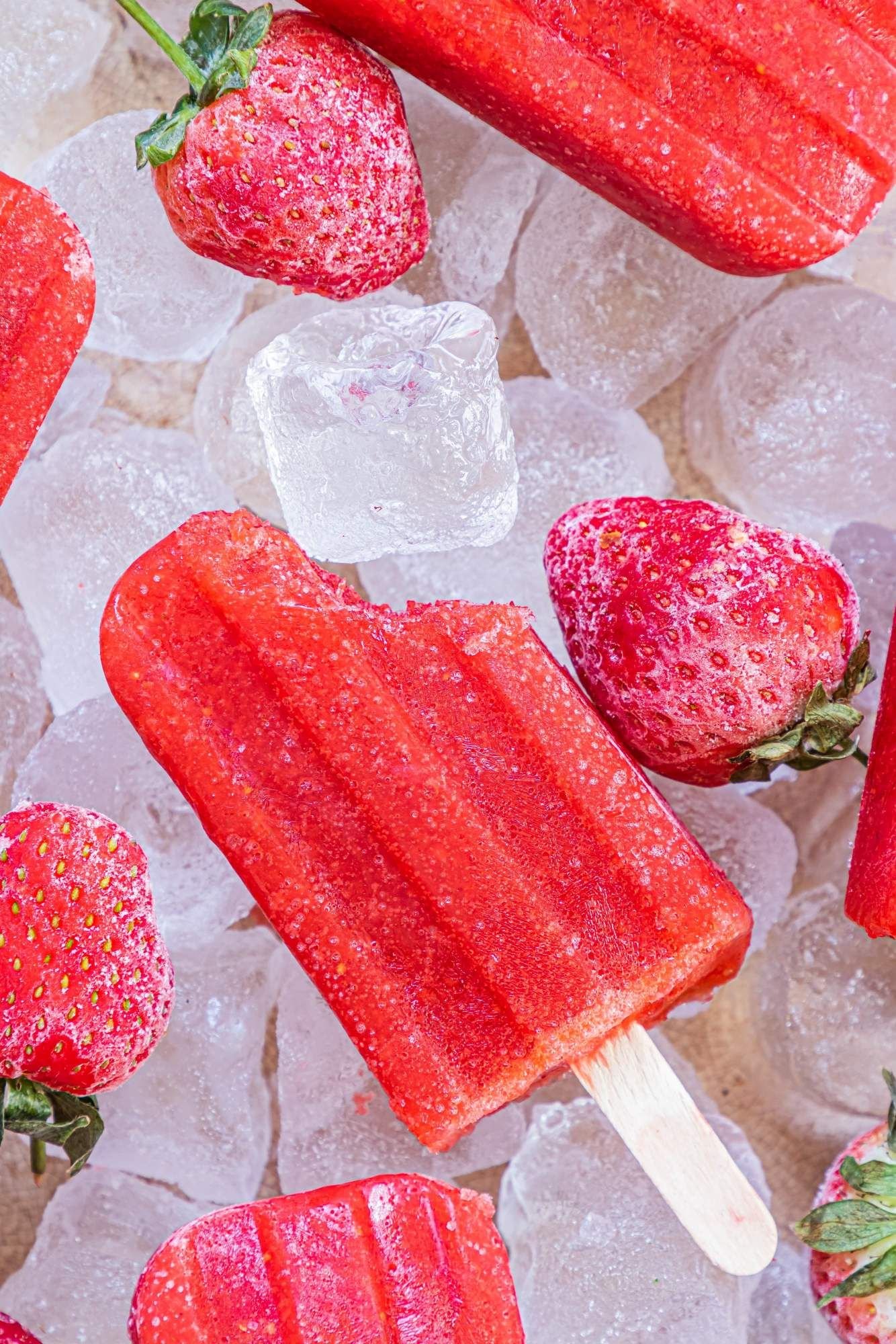 Homemade strawberry ice pops made chopped strawberries and honey served with frozen strawberries and ice.