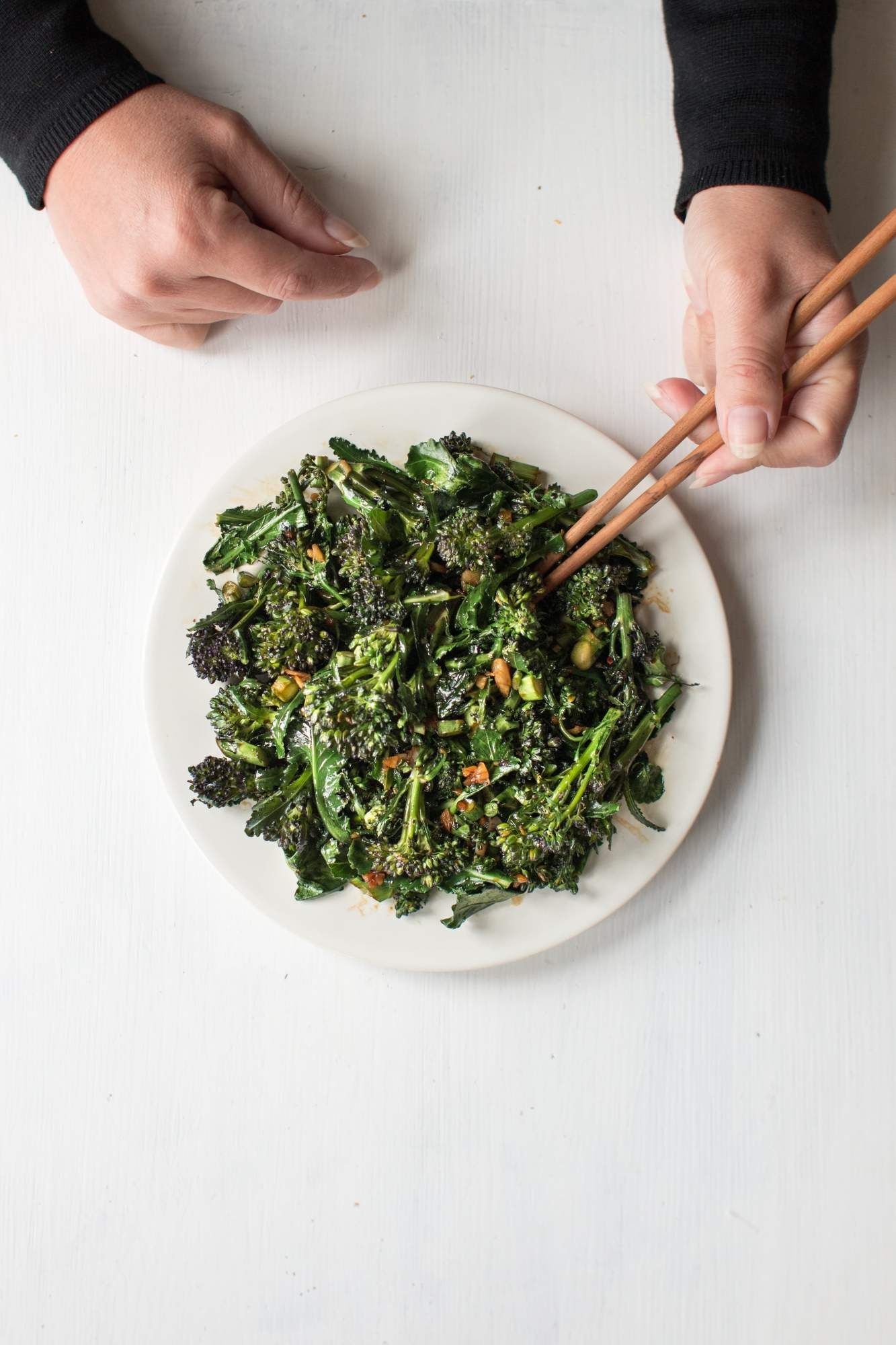 Stir fried chopped Chinese broccoli in a white dish with garlic, ginger, coconut oil, and soy sauce.