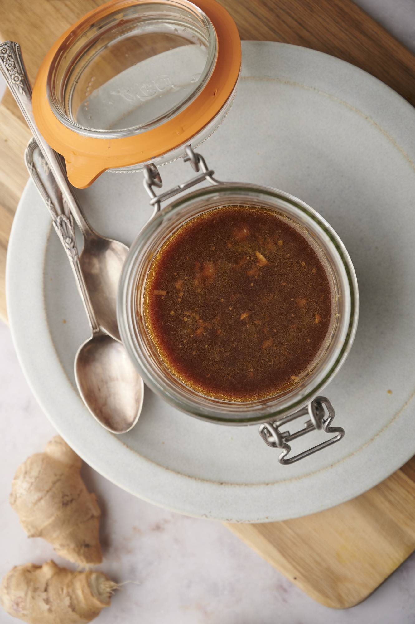 Stir fry sauce with ginger, garlic, soy sauce, honey, and rice vinegar in a jar with a spoon.