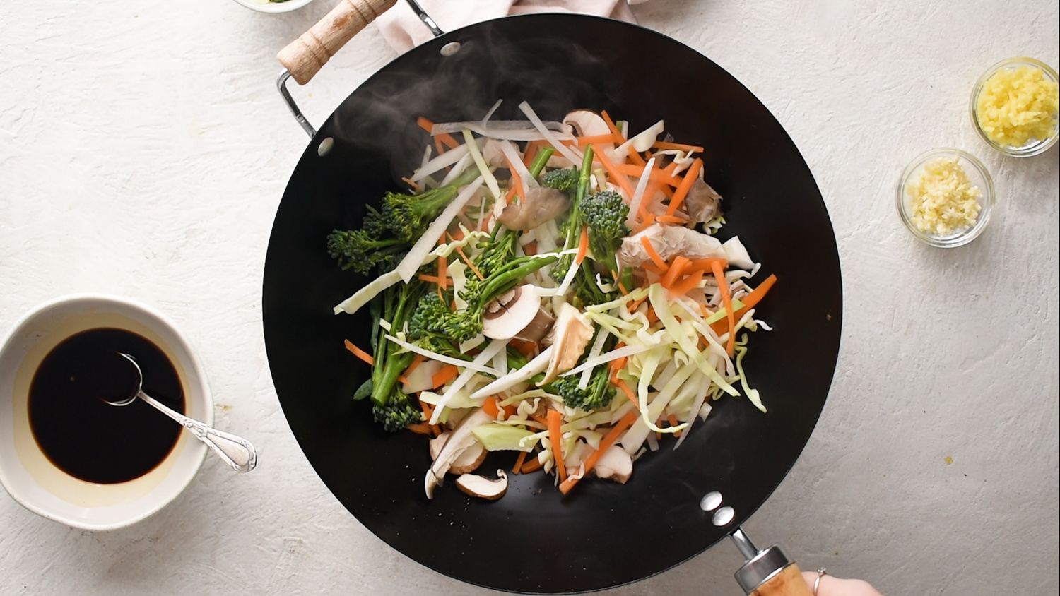 Vegetables in a hot wok with mushrooms, broccoli, cabbage, and carrots.