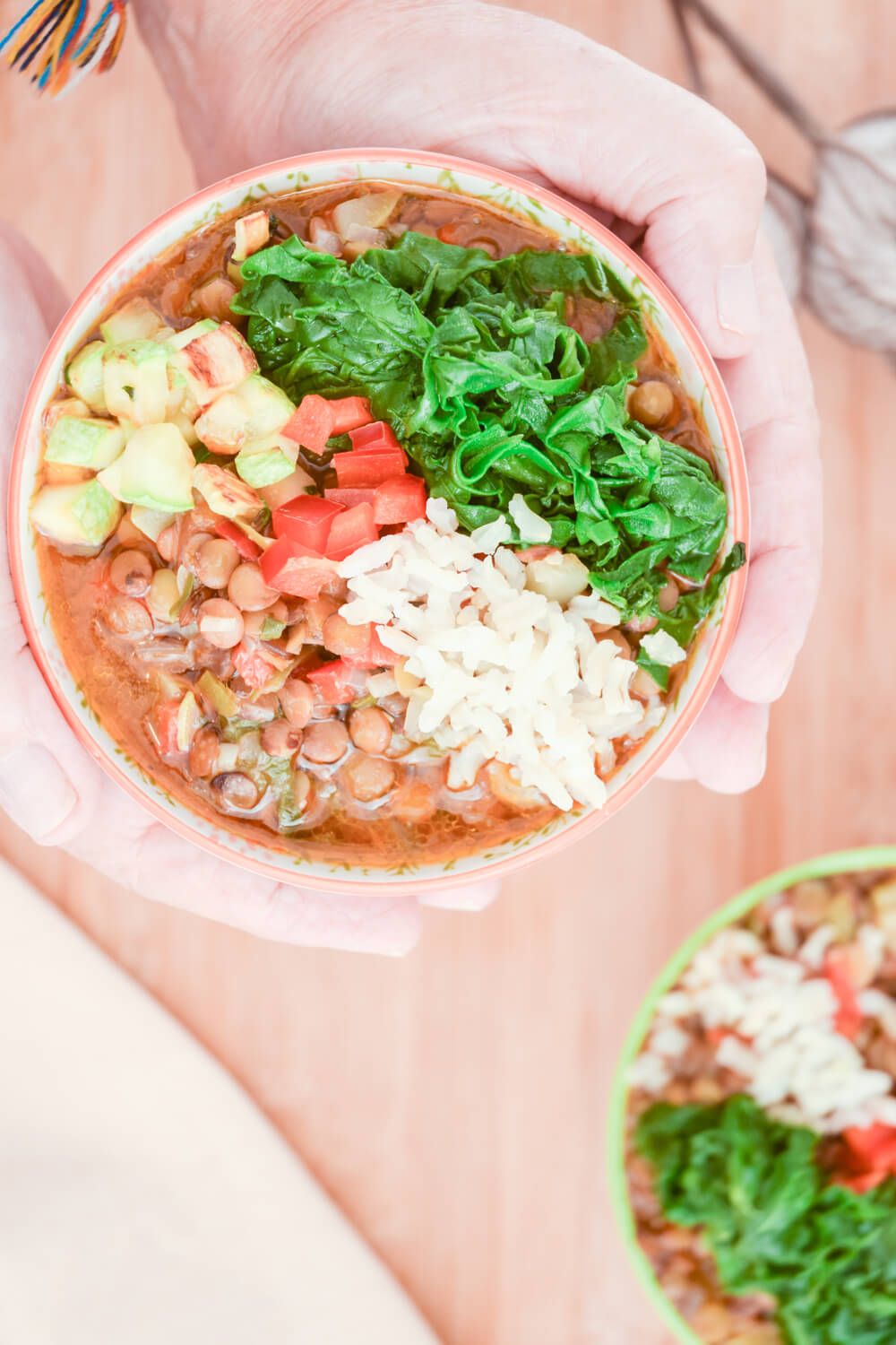 Vegetarian Mexican Lentil Soup cheese and cilantro being held up in a bowl.