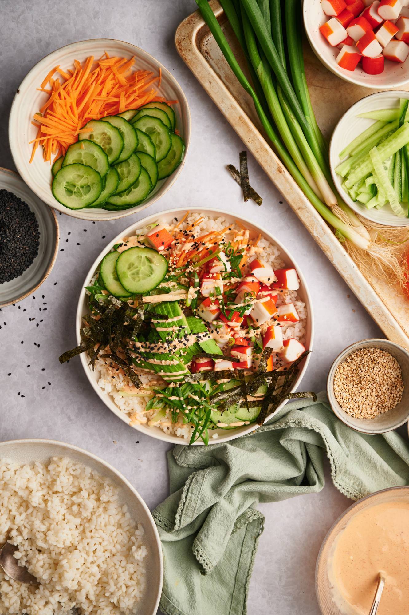 California roll sushi bowl with imitation crab, rice, avocado, carrots, cucmbers, nori seaweed, and sesame seeds.