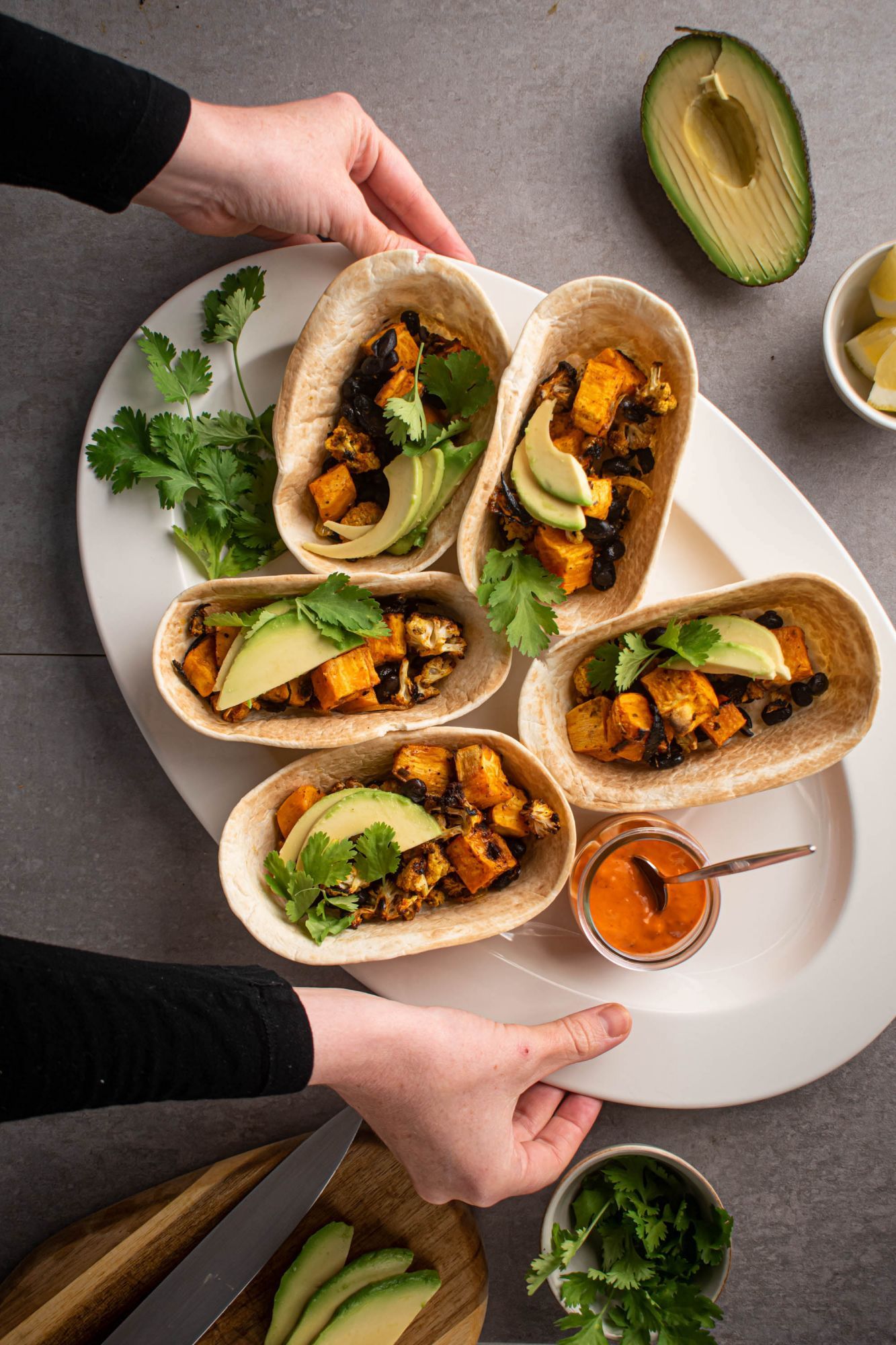 Sweet potato and black bean tacos with cauliflower, avocado, and cilantro in tortillas with salsa on the side.