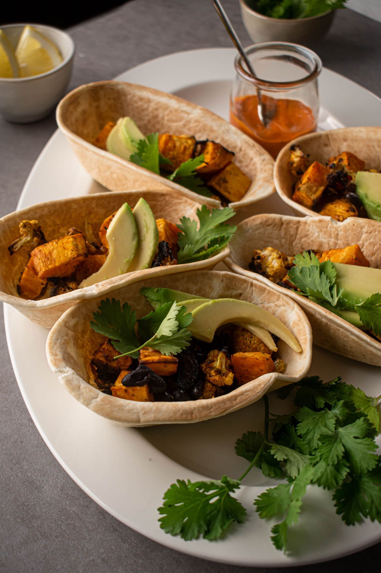 Vegetarian tacos with sweet potatoes, cauliflower, and black beans served with salsa, avocado, and cilantro.