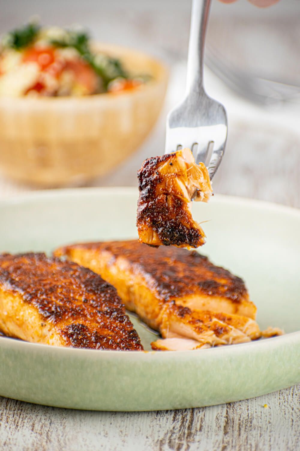 Pan seared salmon with sweet and spicy rub on a plate with a fork.