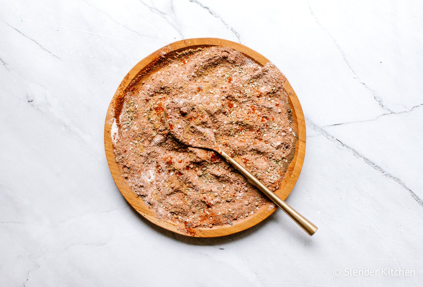 DIY Taco spice blend mixed on a wooden plate with a spoon.