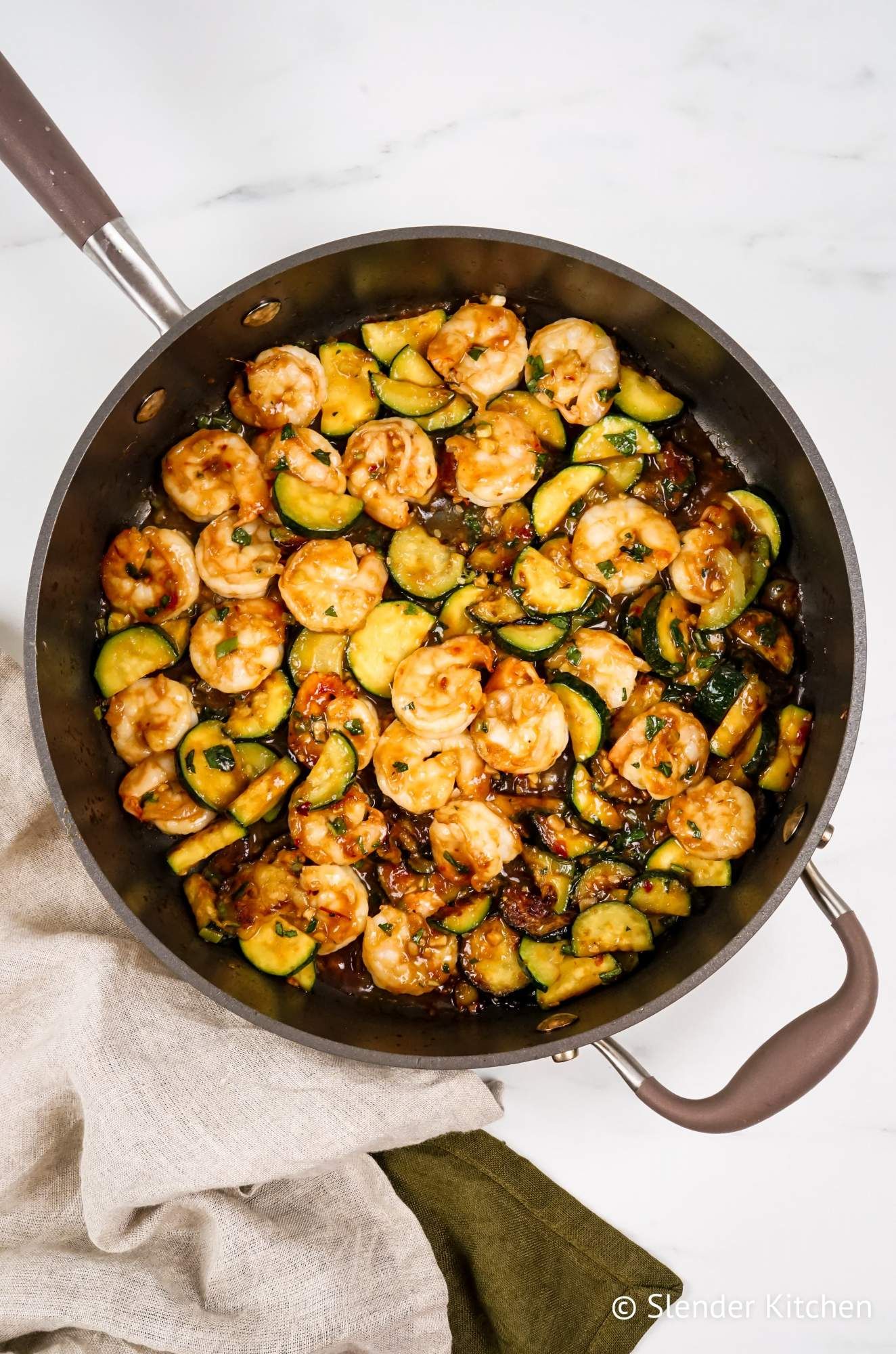 Shrimp stir fry with thai basil and zucchini in a skillet with a spicy stir fry sauce. 