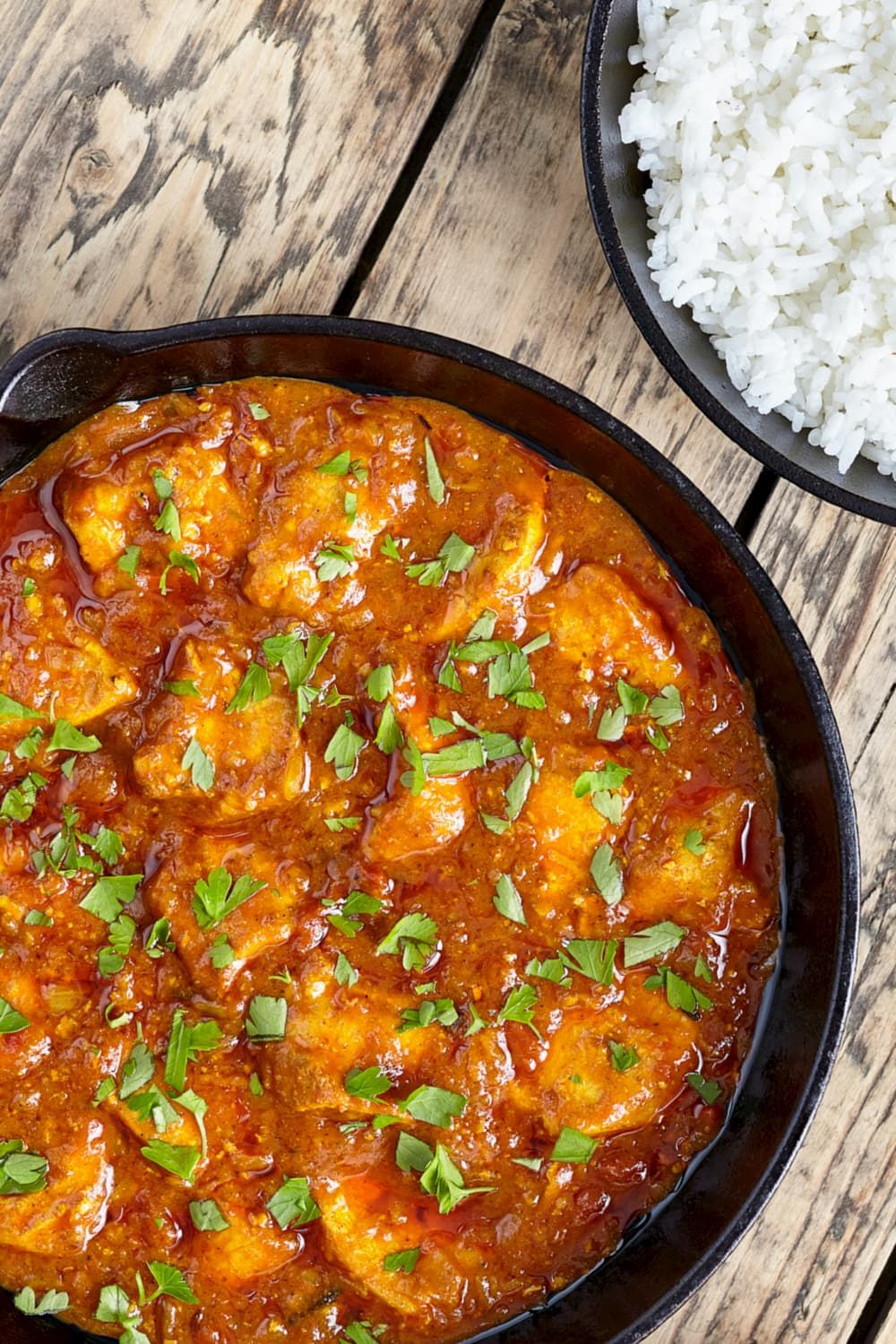 Braised chicken thighs in tomato sauce with chopped parsley.