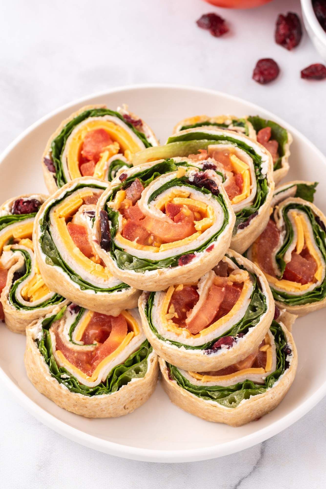 Cream cheese and turkey pinwheels with dried cranberries, deli turkey, cheddar cheese, and vegetables wrapped in a tortilla.