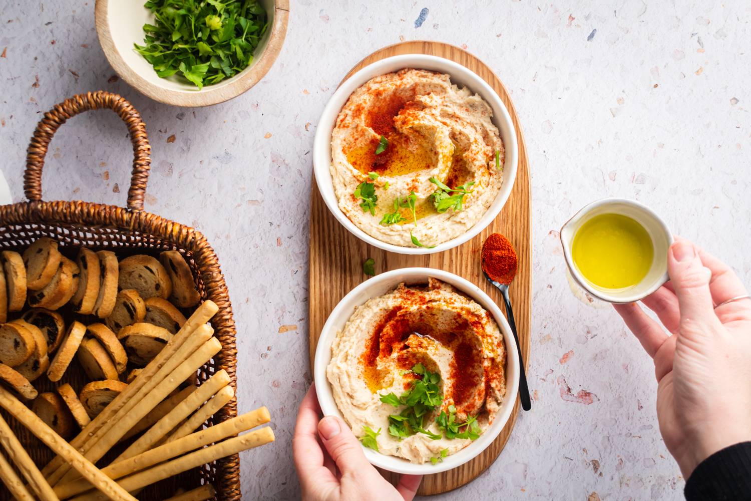 Bean hummus made with white beans in a bowl with breadsticks and crostini on the side.