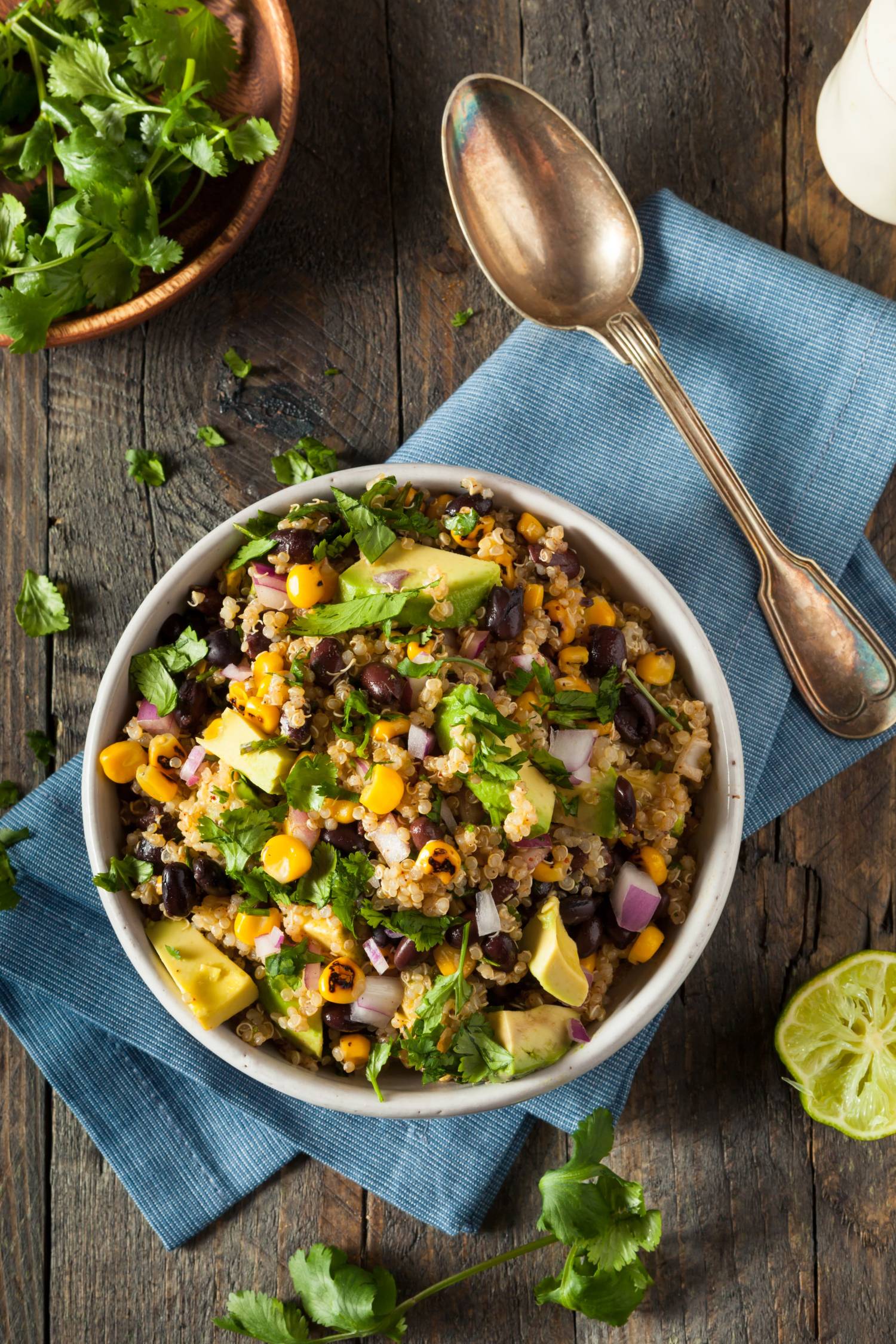 Mexican quinoa salad in a bowl with avocado, black beans, quinoa, cilantro, and corn.