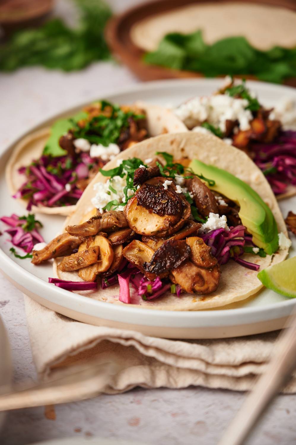 Crispy mushroom tacos with roasted mushrooms, avocado, cilantro, cabbage slaw, and cheese in a folded corn tortilla.