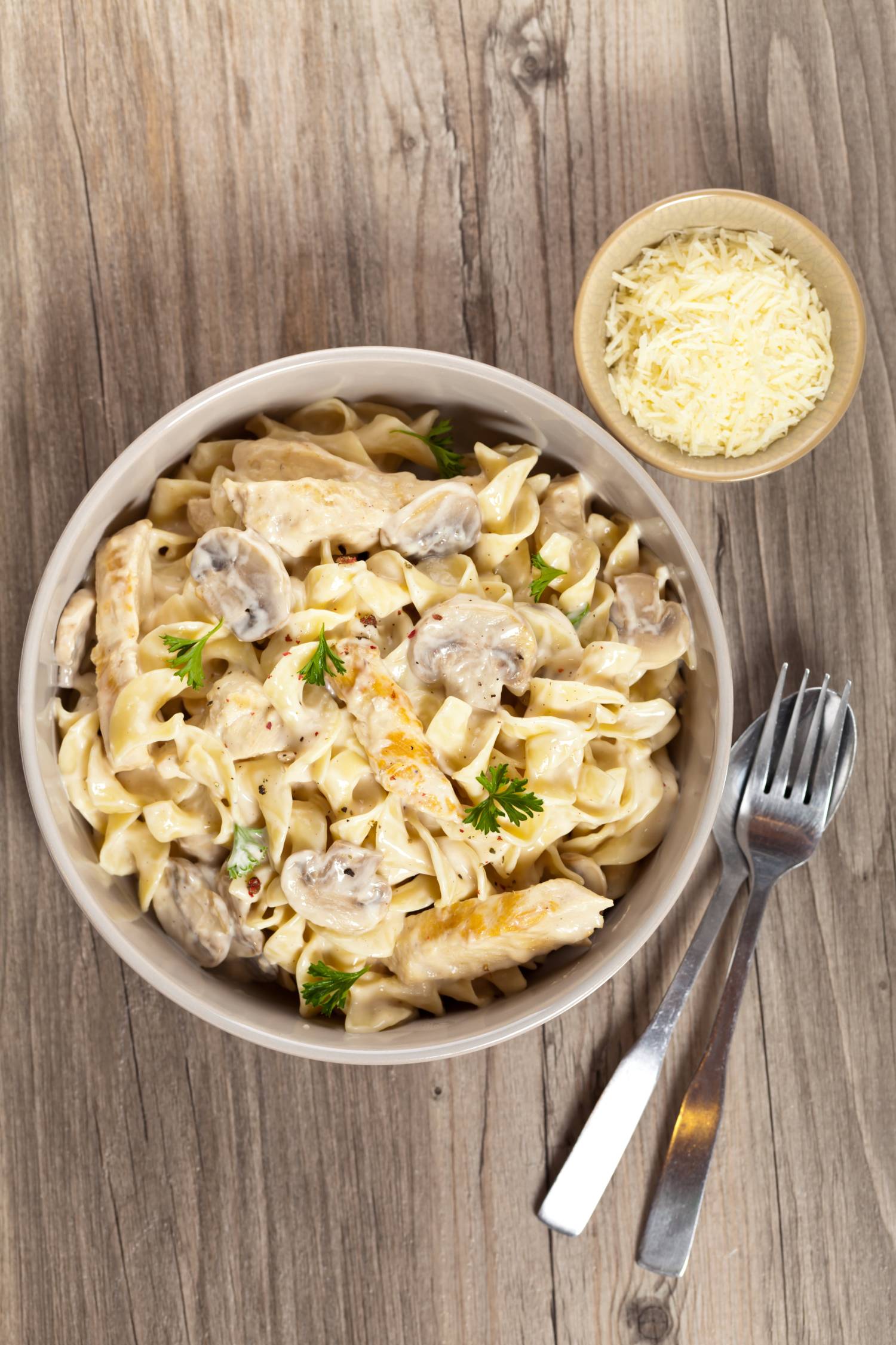 Chicken mushroom pasta with a creamy sauce and Parmesan cheese in a bowl.