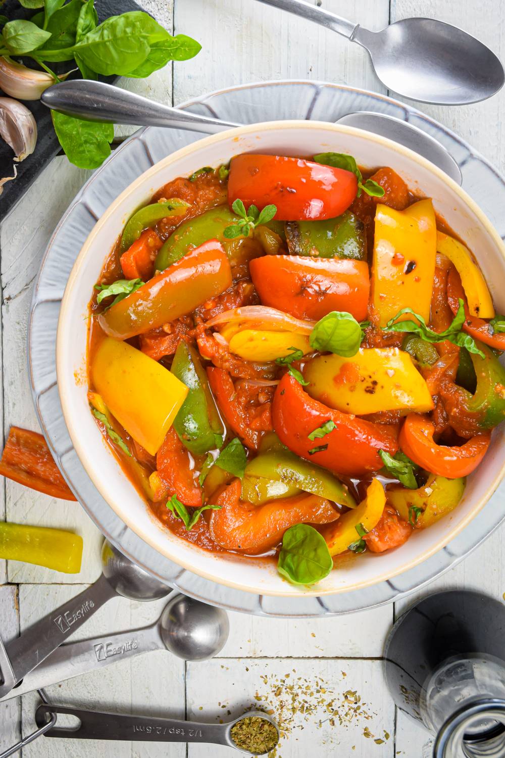 Pepperonata in a bowl with red, green, and yelllow pepper with fresh herbs.