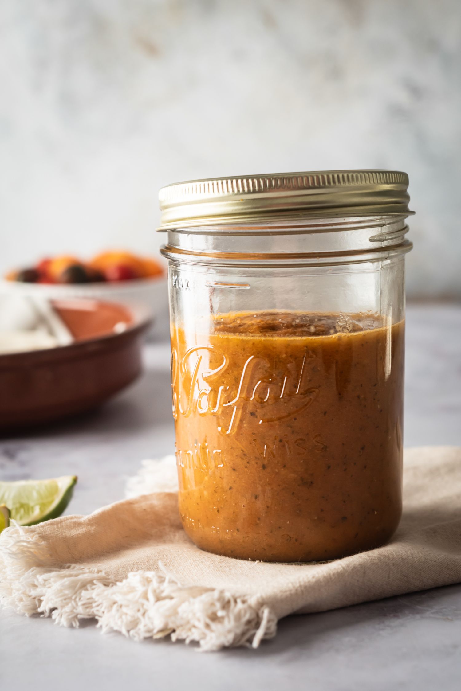 Jar of homemade tomato ranchero sauce with a napkin with tomatoes on the side.