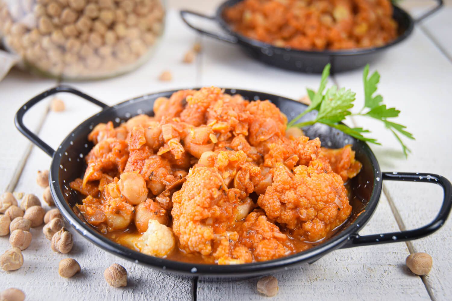 Slow cooker chickpea tikka masala with cauliflower in a bowl with tomatoes and Indian spices.