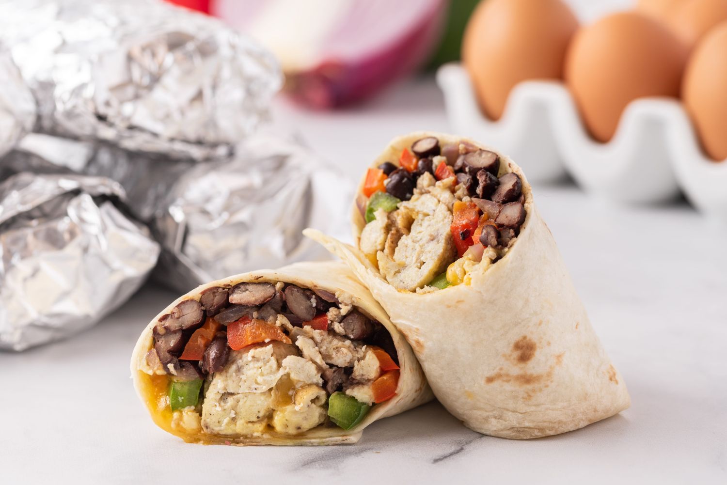 Freezer breakfast burritos with eggs, black beans, peppers, and onions wrapped in a tortilla.