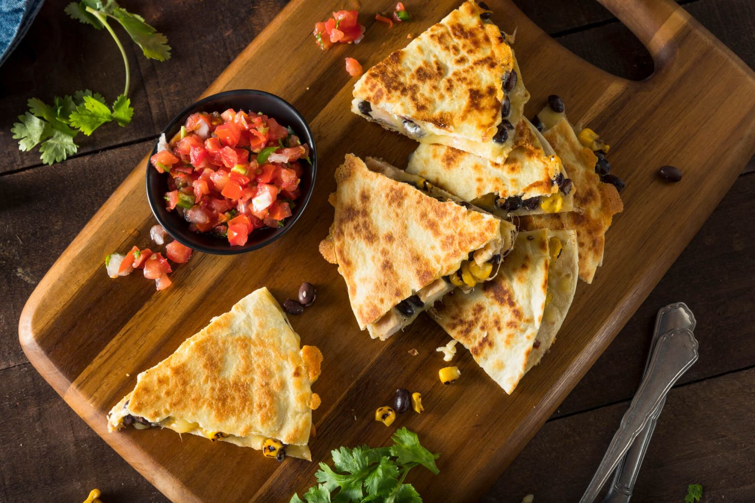 Chicken quesadillas cut into wedges with chicken, melted cheese, and beans on a cutting board.