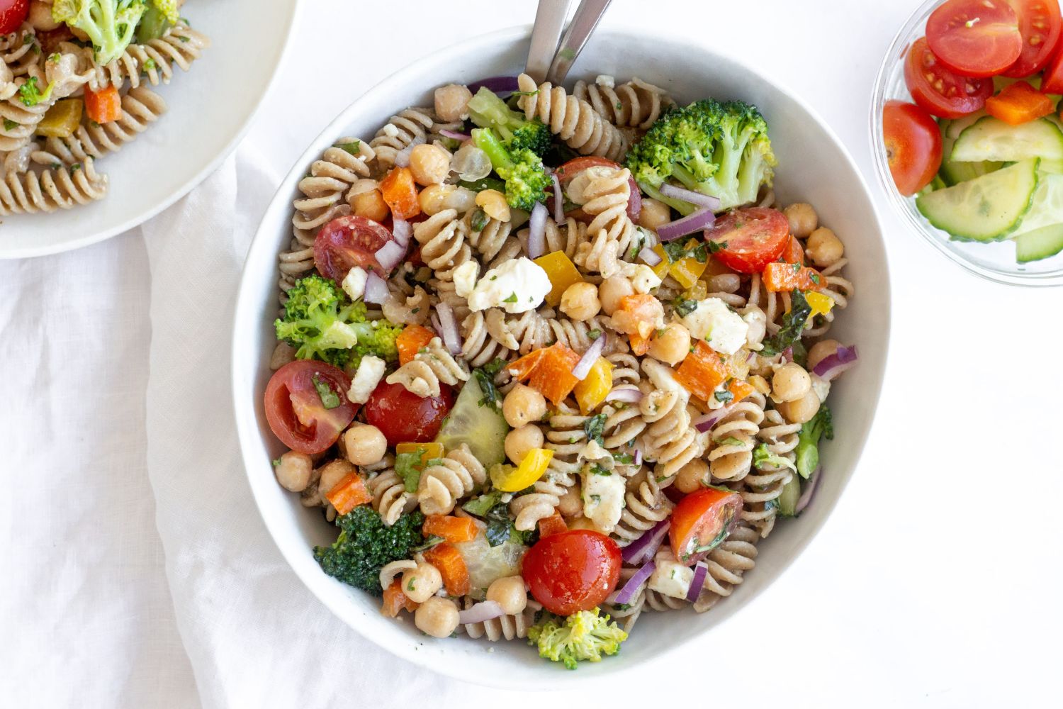 Vegetable pasta salad with whole wheat pasta, chickpeas, tomatoes, cucumbers, and fresh herbs in a homemade salad dressing.