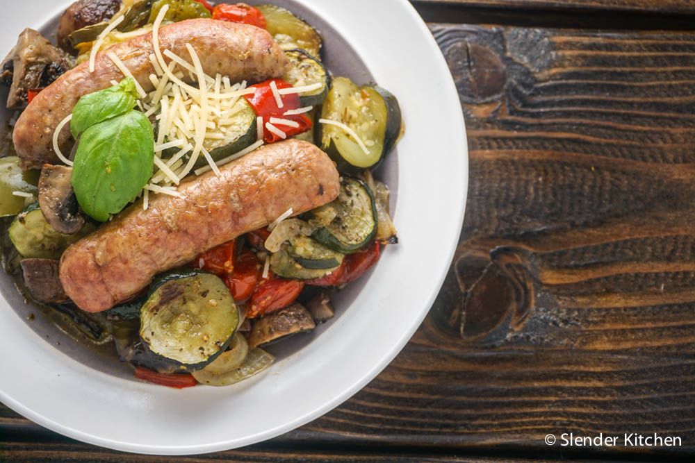 Italian sausage with tomatoes, zucchini, and onions in a bowl with a cloth napkin.