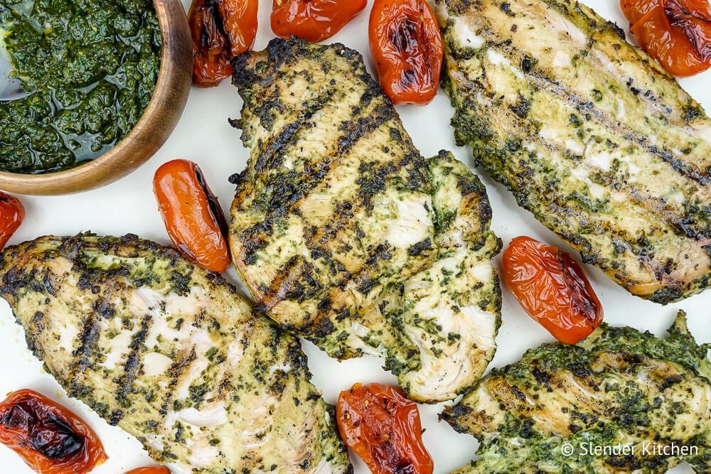 Skinny pesto sauce with chicken with tomatoes on a marble board.