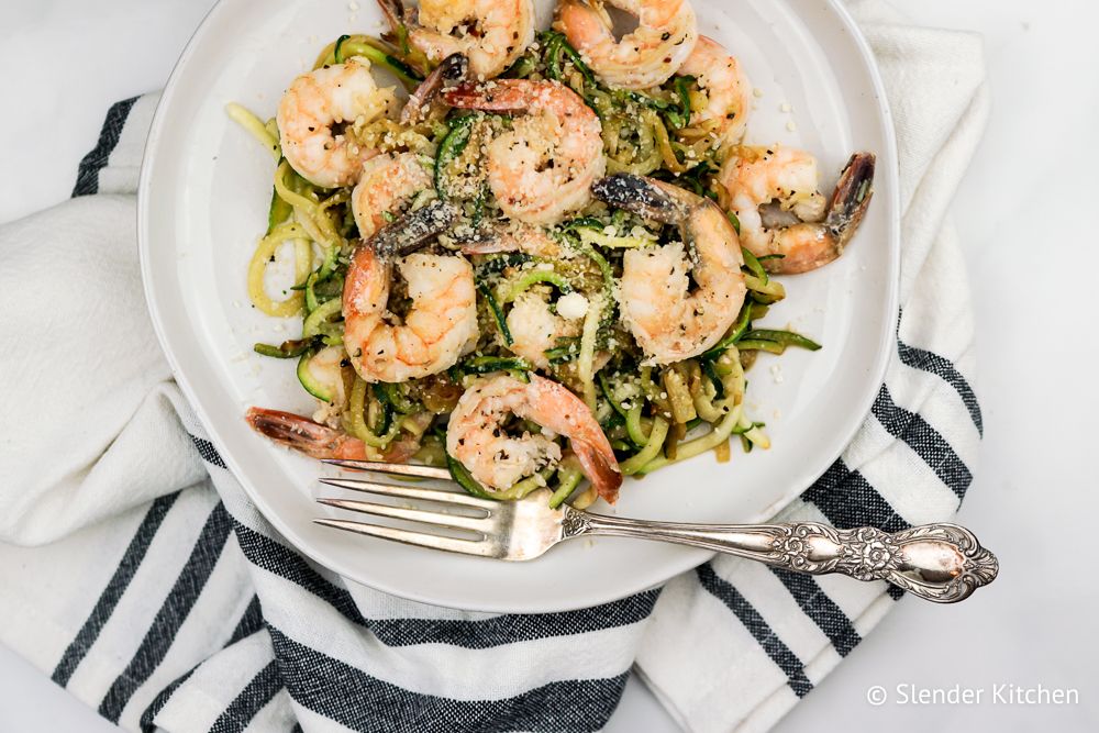 Zoodles with shrimp and Parmesan cheese on a white plate.