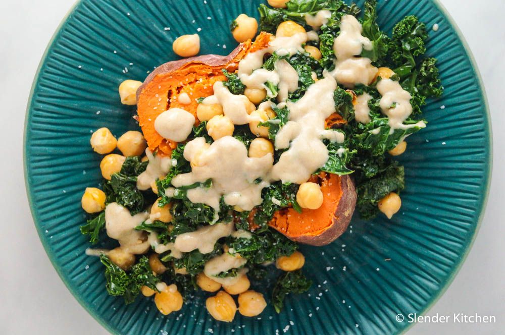 Baked sweet potato with chickpeas and kale on a blue plate.