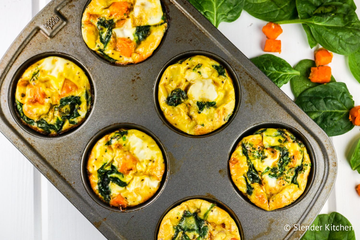 Sweet potato, egg, and spinach muffins in a muffin tin.